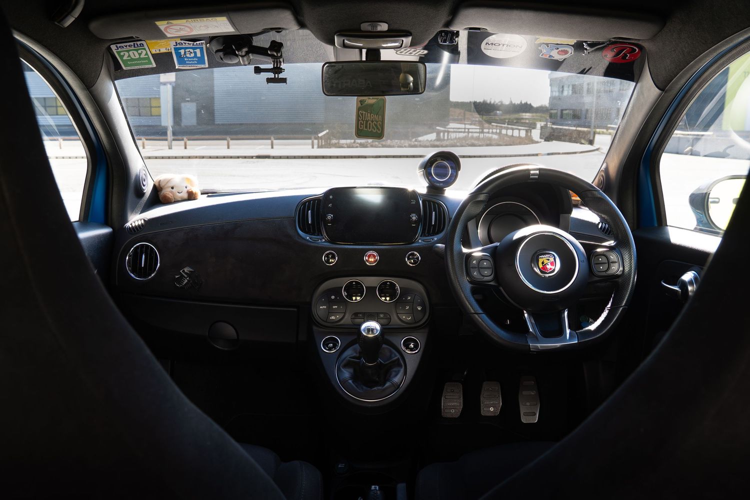 Dashboard view of an Abarth 500 showing the touchscreen infotainment, Abarth steering wheel, and instrument cluster.