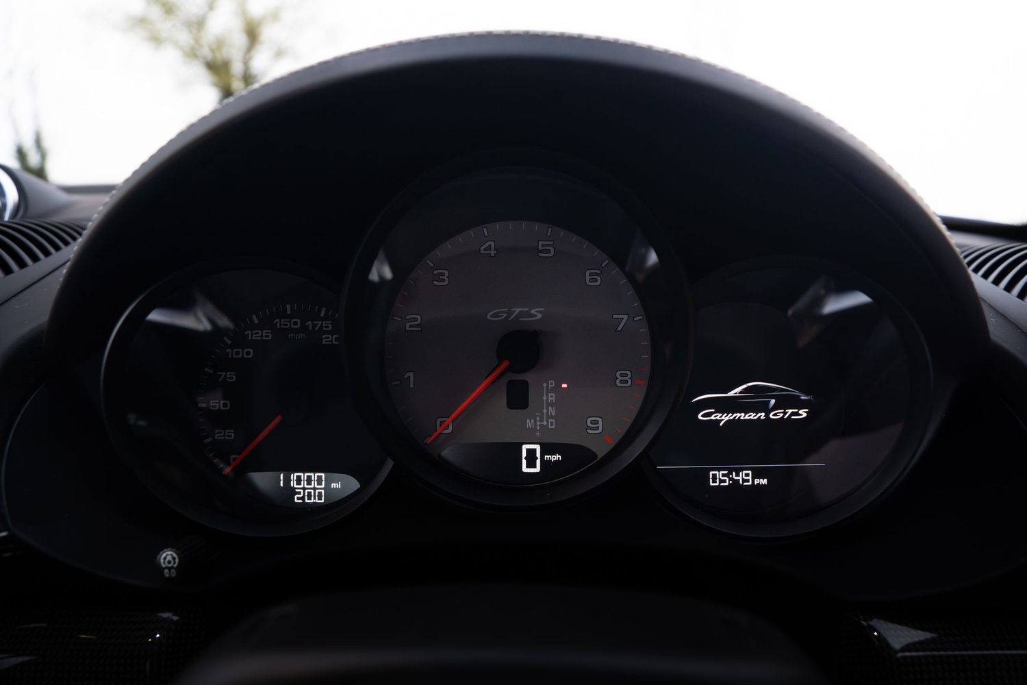 Porsche Cayman GTS instrument cluster displaying tachometer and digital screen with car logo.