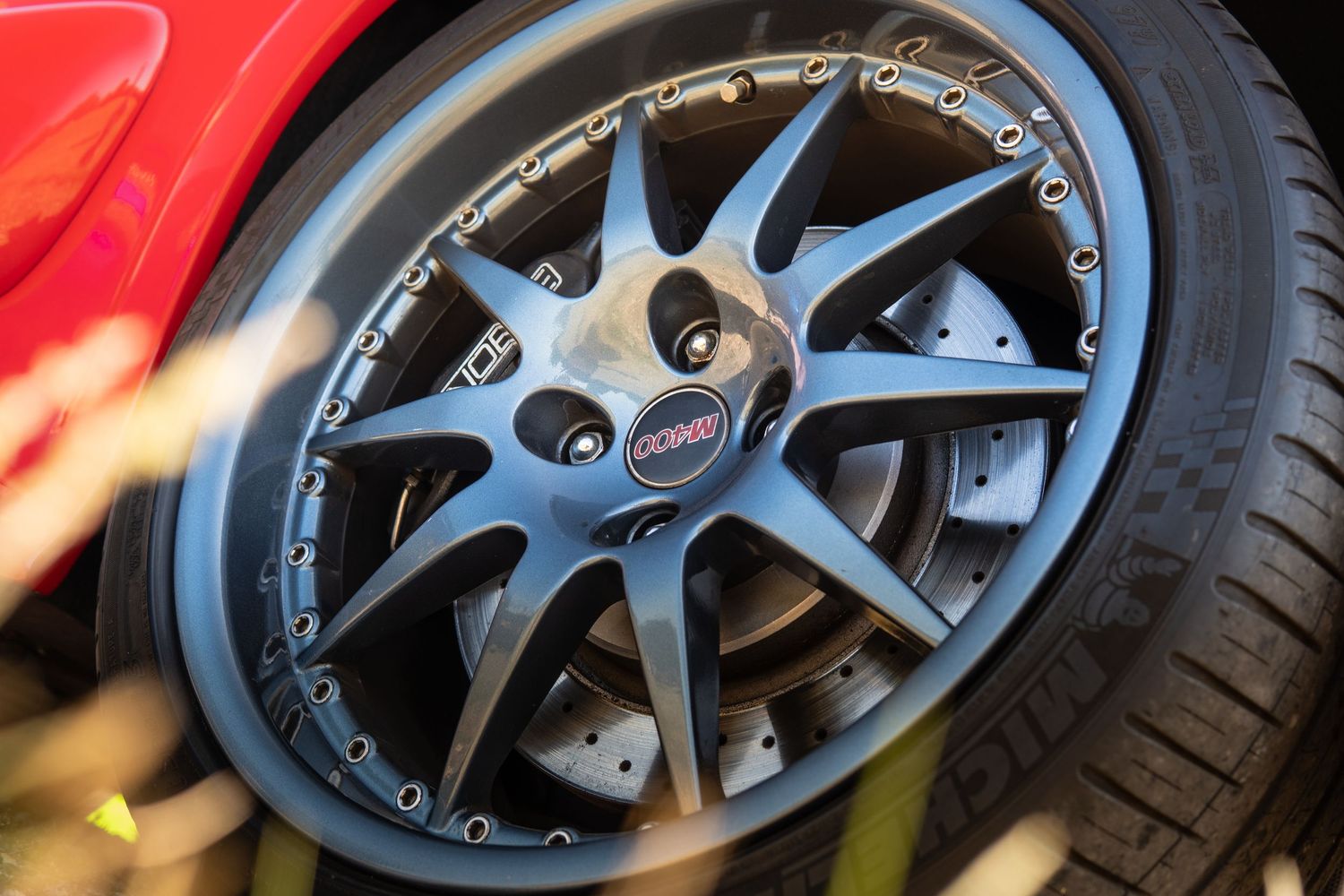 Close-up of dark multi-spoke alloy wheel with red brake caliper on sports car.