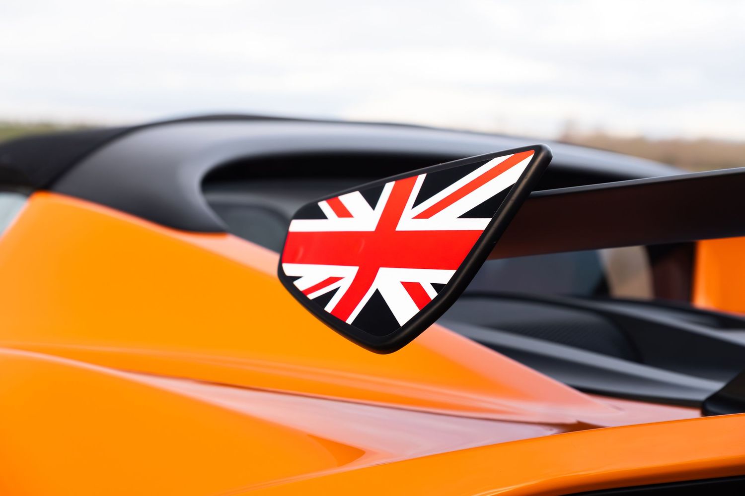 Union Jack flag emblem badge on the side of an orange Lotus sports car.