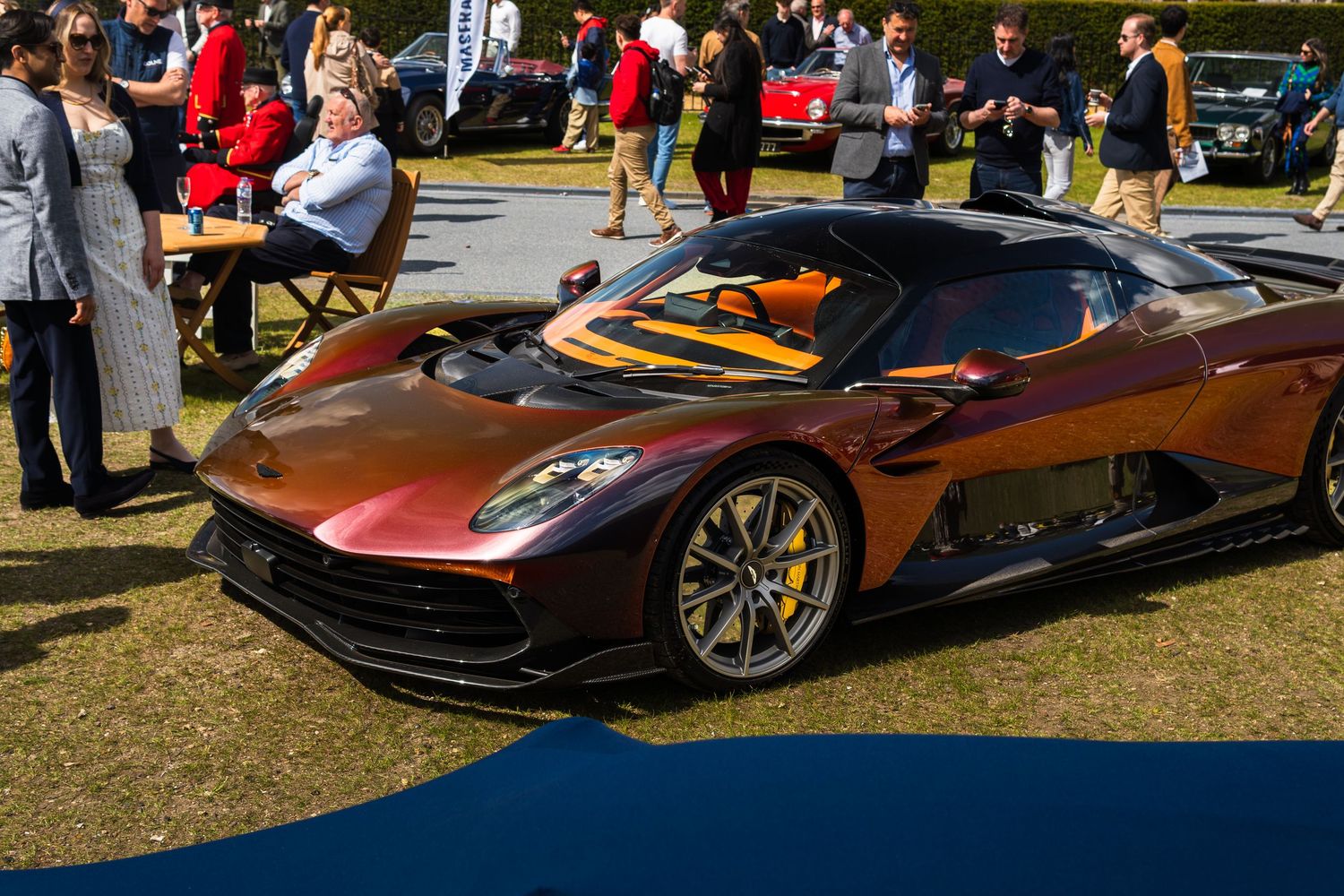 Stunning dark red Aston Martin Vulcan hypercar on display at an exclusive outdoor automotive concours event.