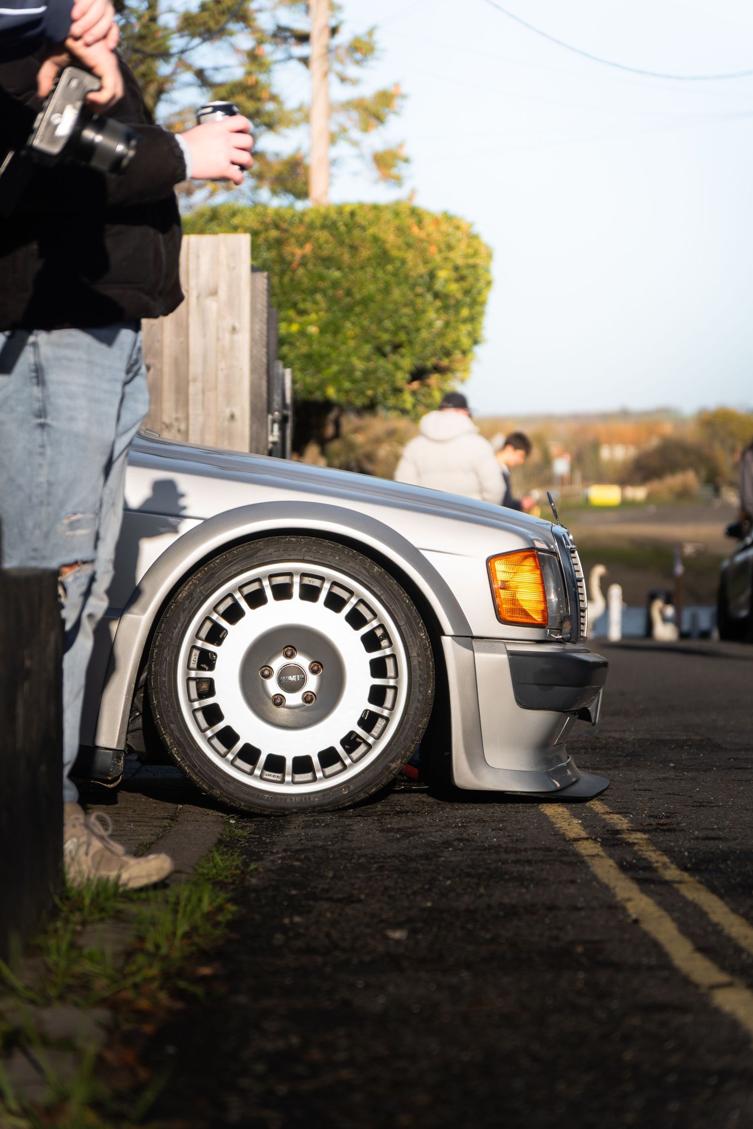 Close-up of a silver Mercedes 190E Evo with wide arch kit and BBS alloy wheels at a car show.