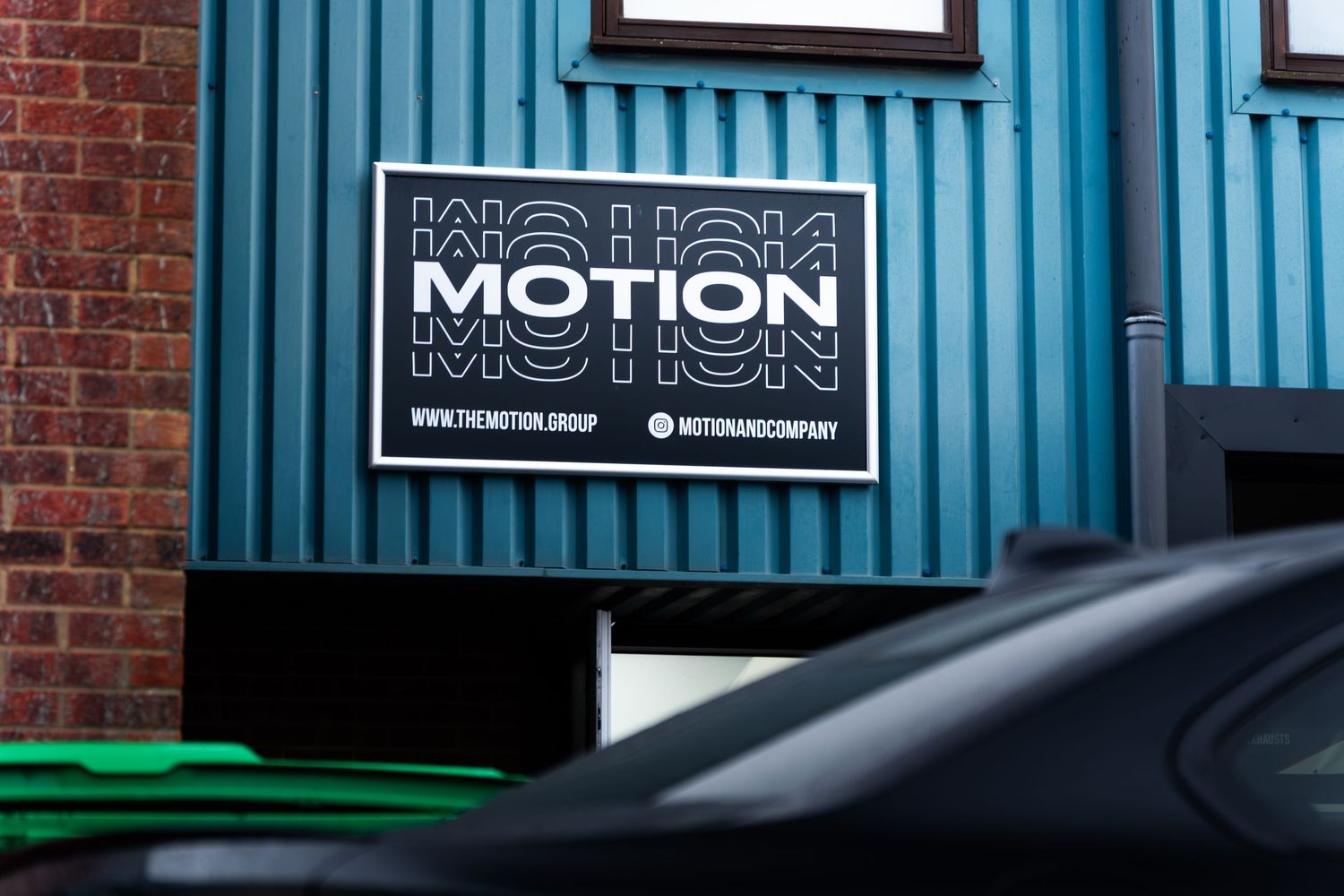 Motion automotive company signage on a teal blue building exterior.