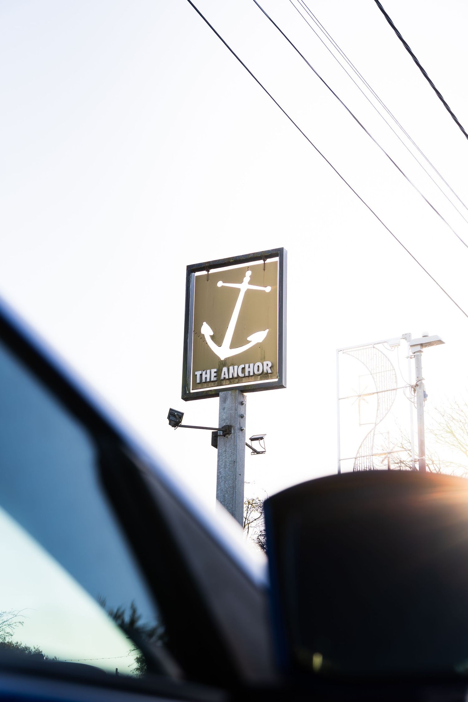 The Anchor pub sign mounted on a pole featuring a white anchor logo against a dark background.