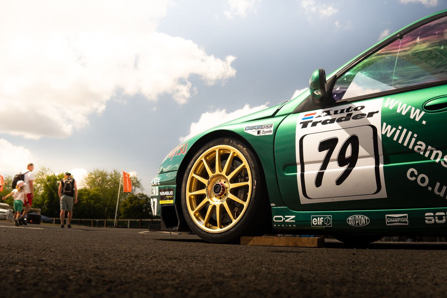 Green Williams AutoTrader number 79 race car with gold OZ wheels at motorsport event.