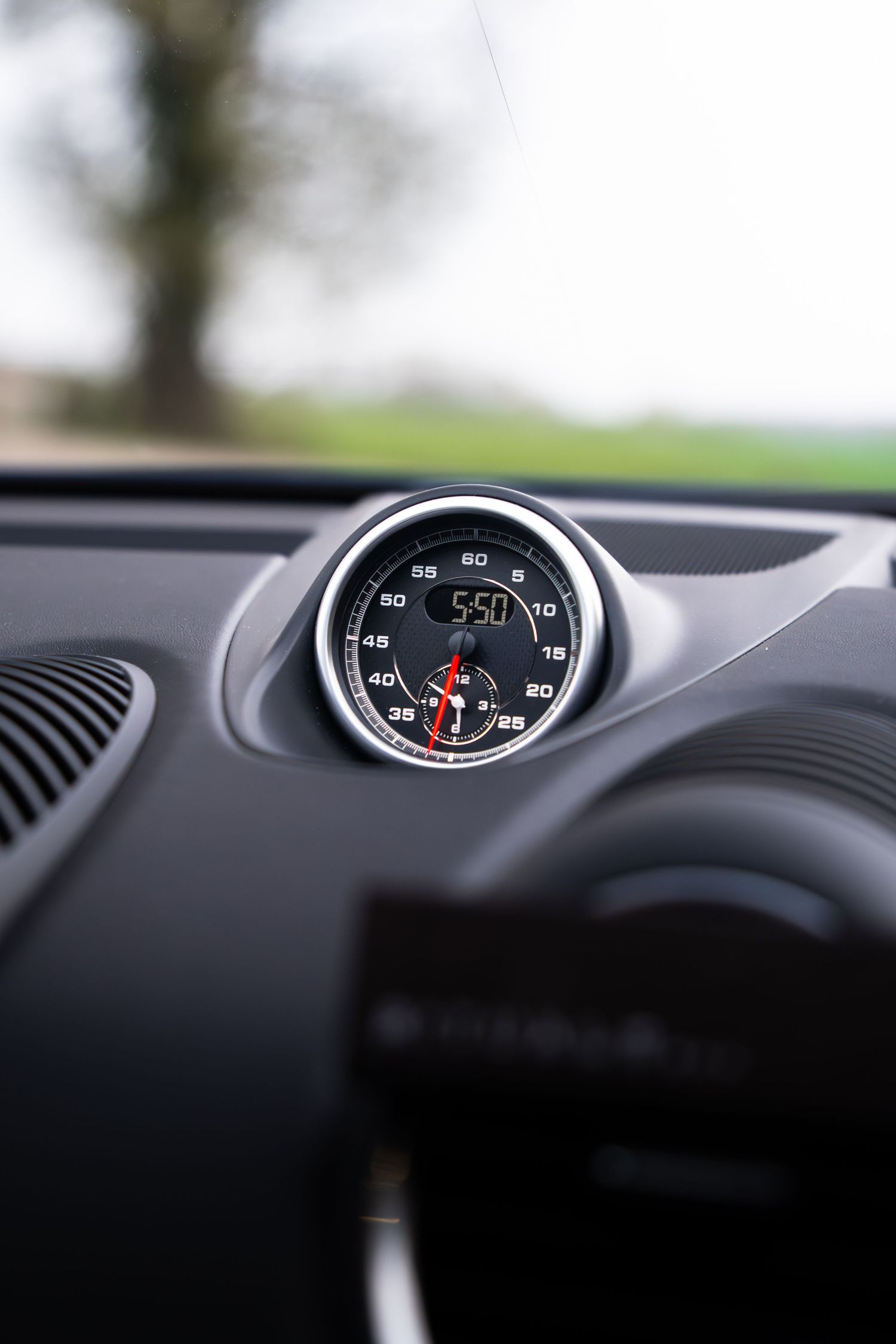 Porsche Cayman GTS dashboard-mounted analog clock and boost gauge showing 550 reading.