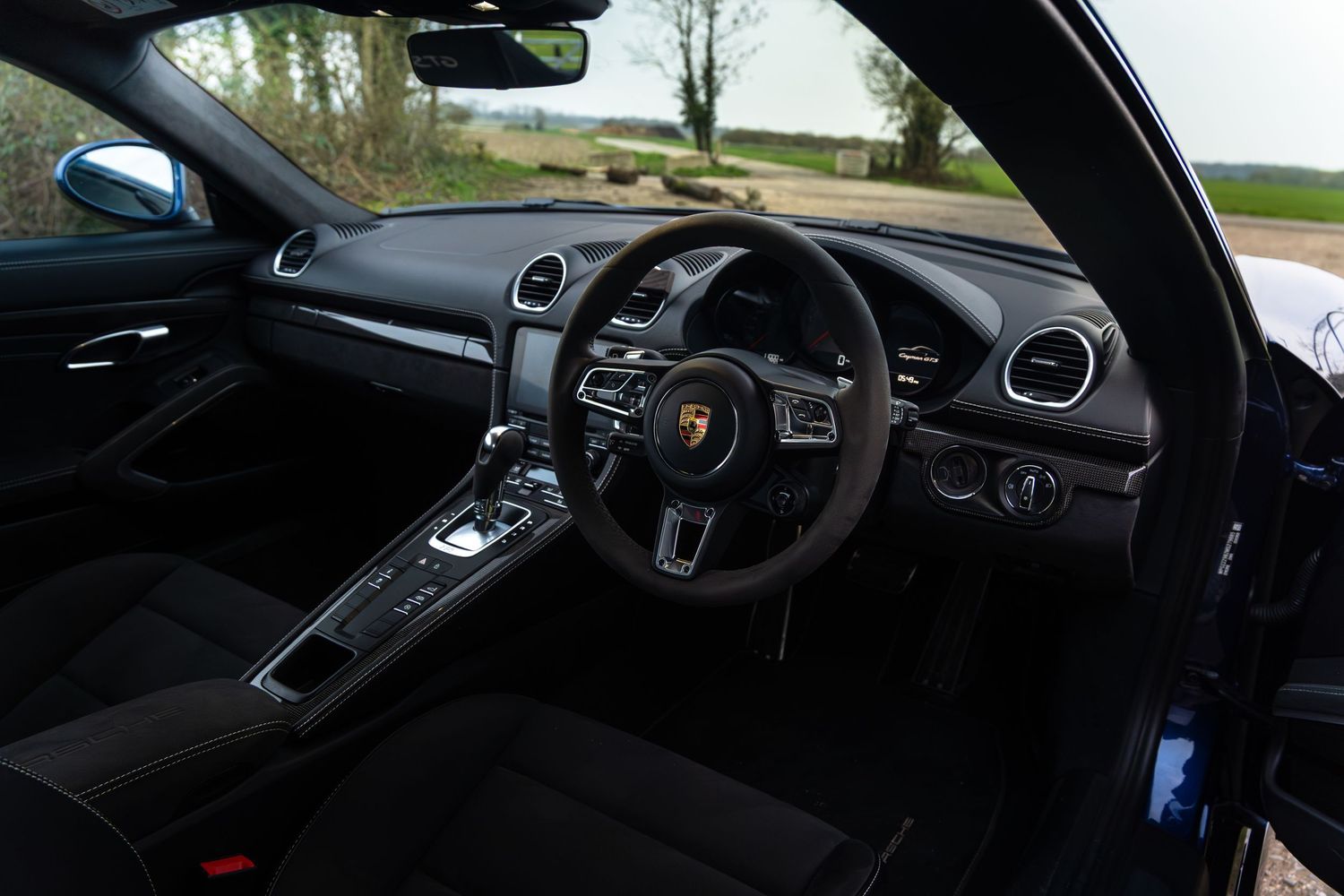 Porsche Cayman GTS right-hand drive cockpit with black leather interior and sport steering wheel.
