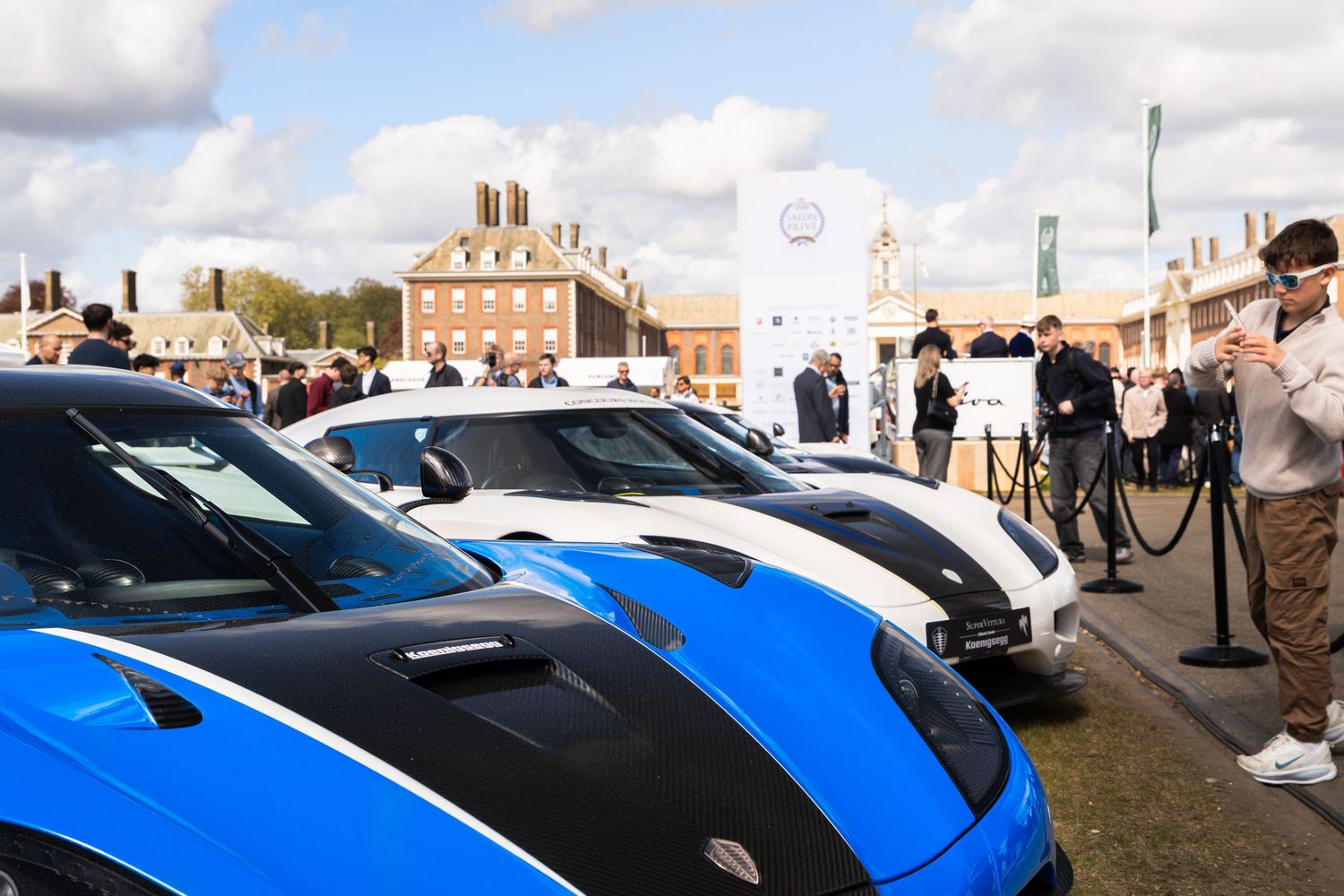 Row of blue and white Koenigsegg supercars on display at Salon Prive luxury car show.
