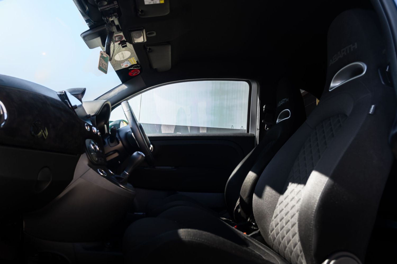 Interior view of an Abarth sports car showing black bucket seats with diamond stitching and a compact cabin.