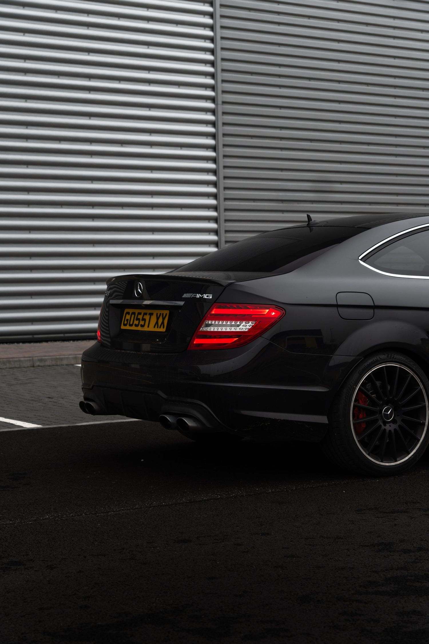 Rear view of a black Mercedes-AMG C63 coupe showing LED taillights and AMG badge details.