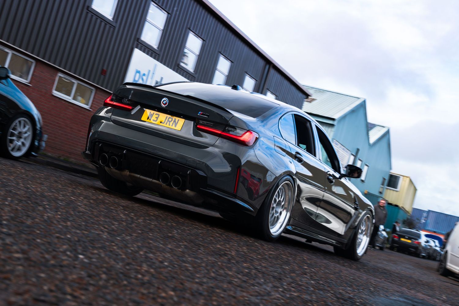 Black BMW M3 G80 lowered on silver BBS wheels parked outside industrial unit in the UK.