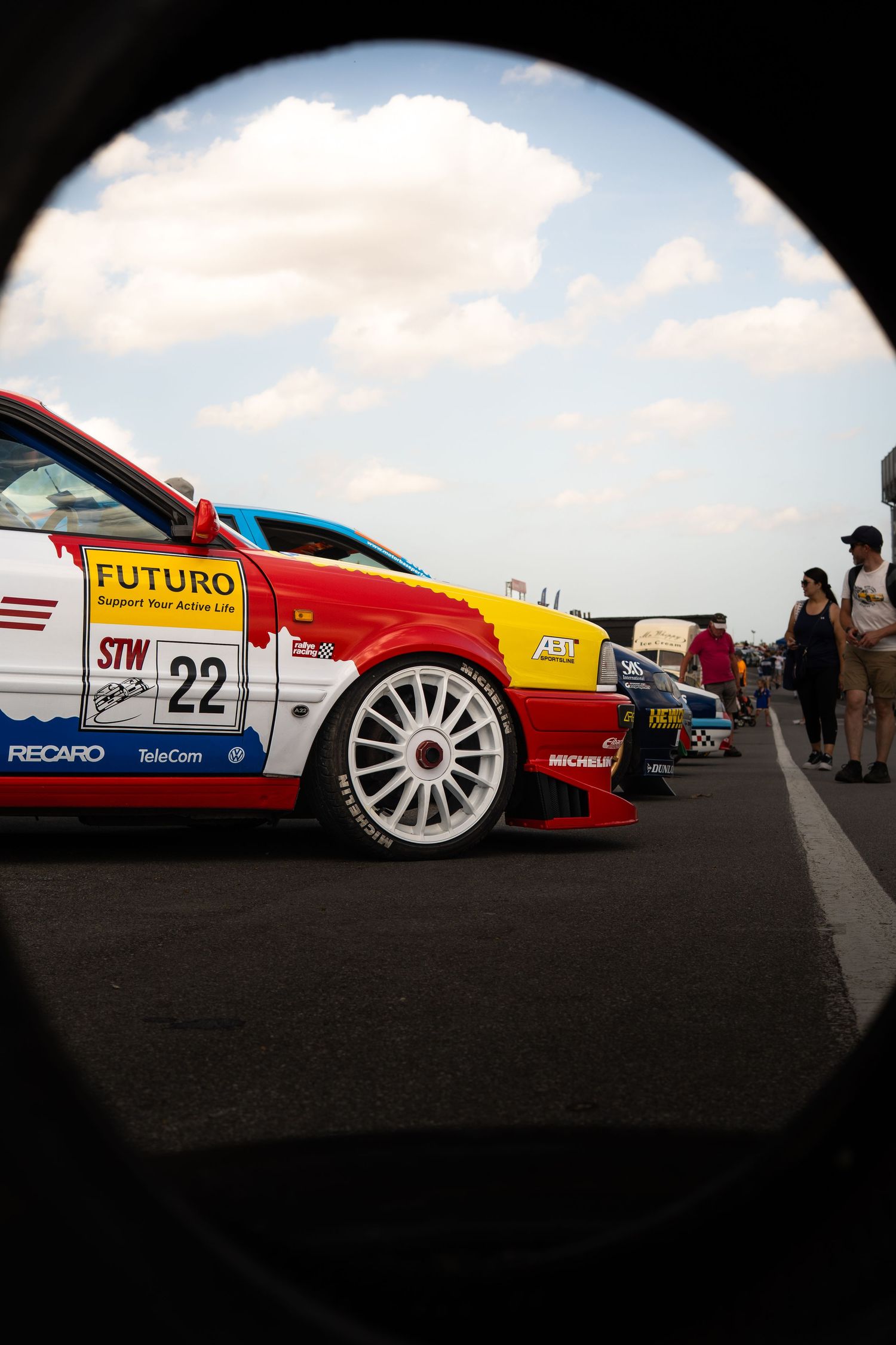 A red and white number 22 Futuro STW race car on track viewed through a circular frame.