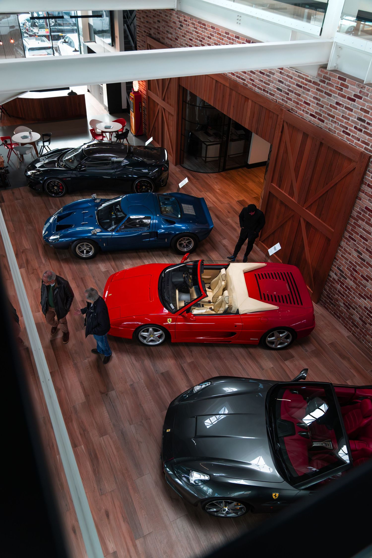 Aerial view of Ferrari collection including red convertible, blue and black supercars in showroom.