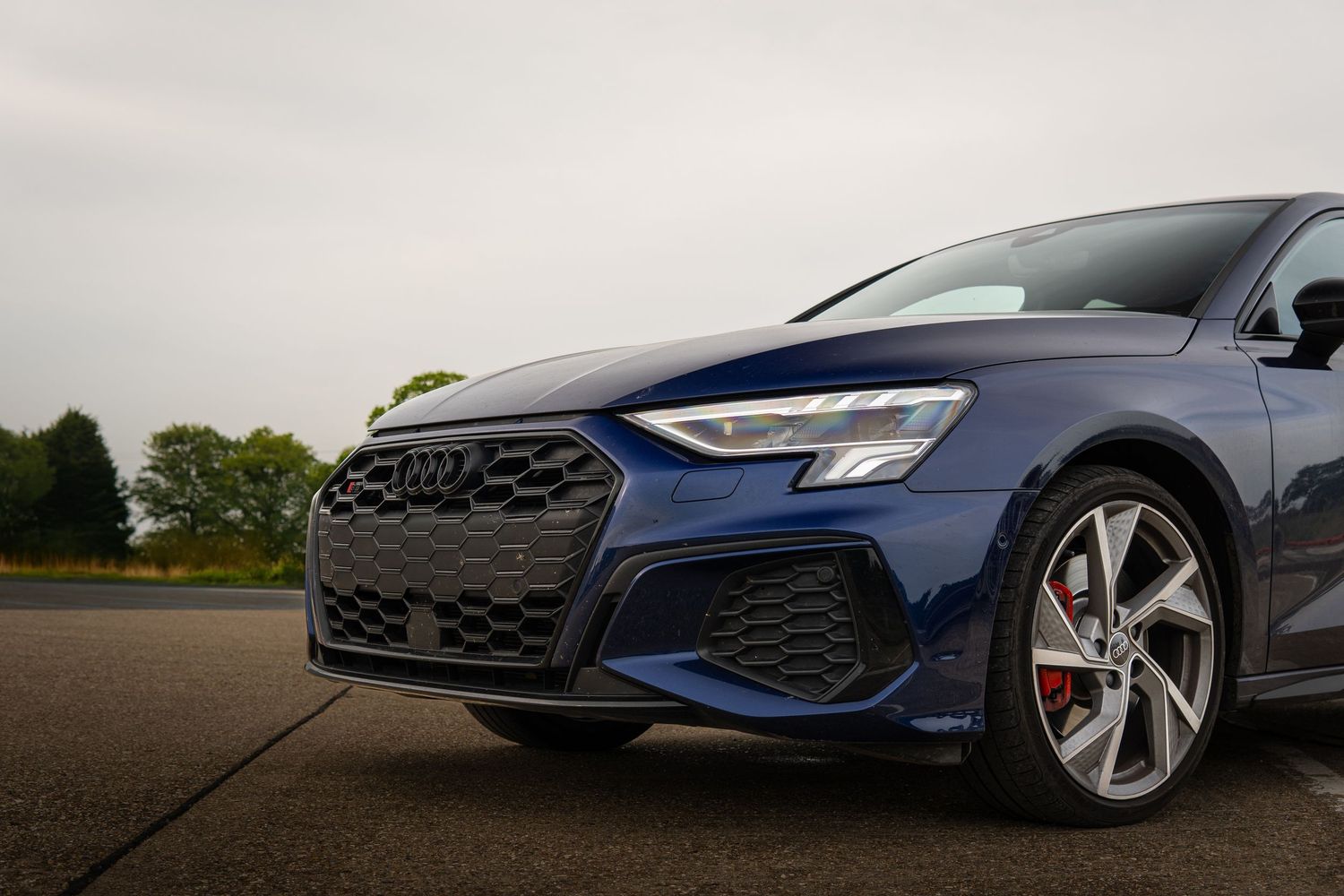 Low-angle front corner view of a navy blue Audi S3 highlighting the grille and headlights.