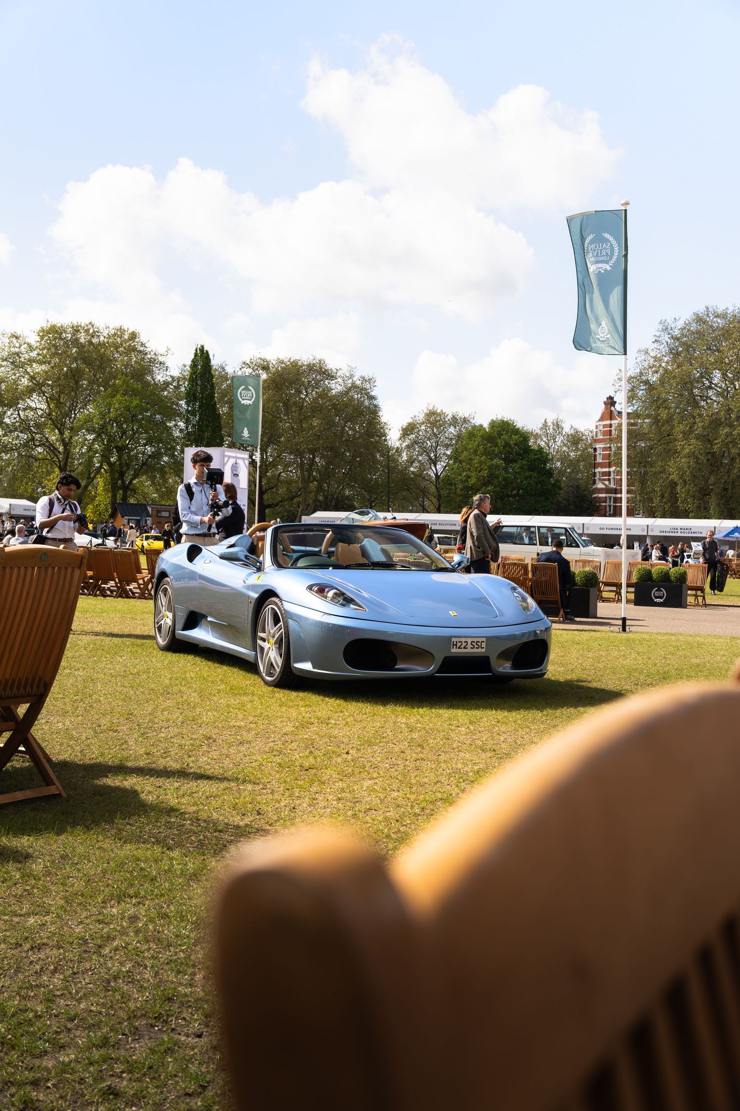 Silver Ferrari F430 Spider on display at an outdoor classic car show on a sunny day.