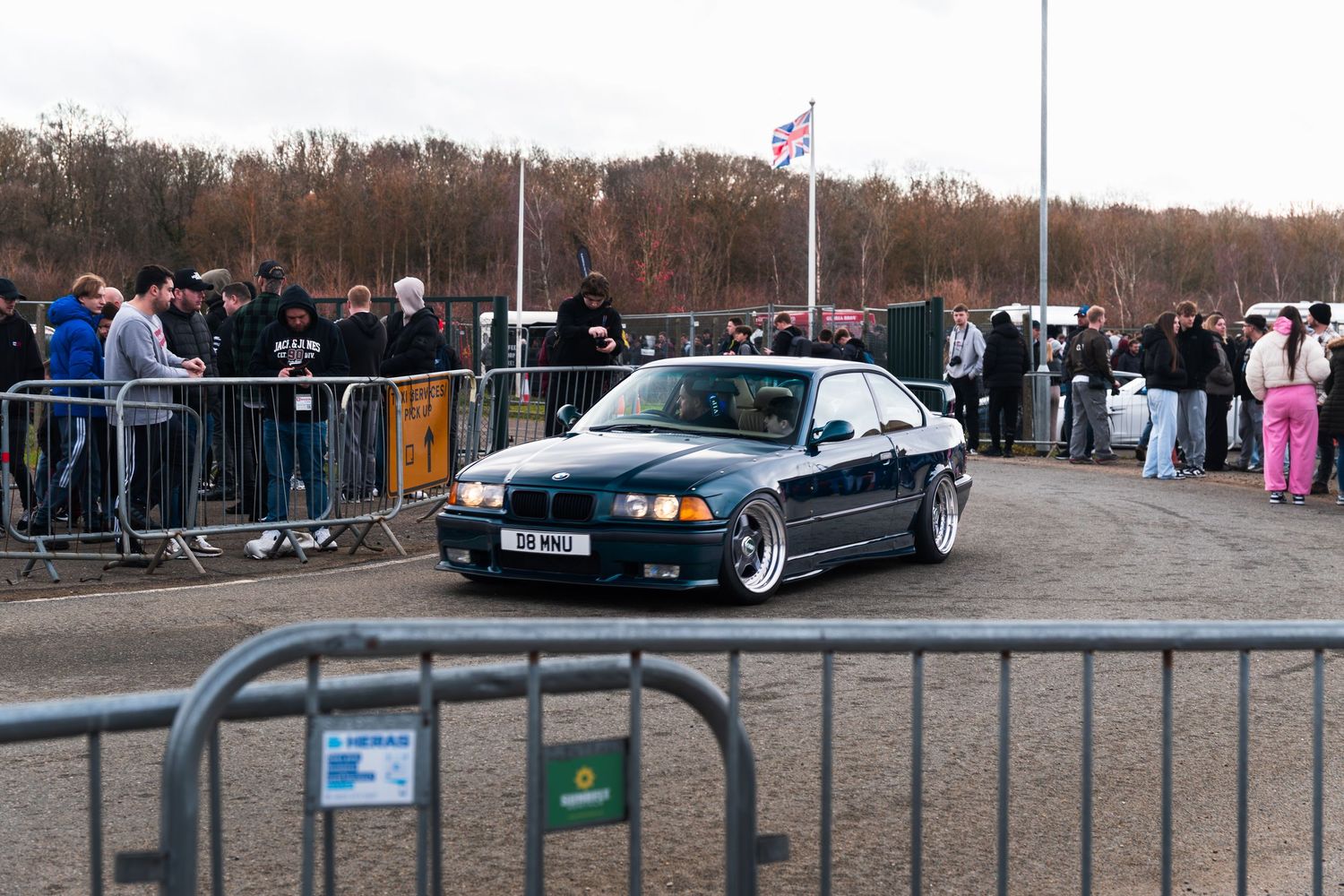 Green BMW E36 coupe on lowered suspension at a UK car show event.