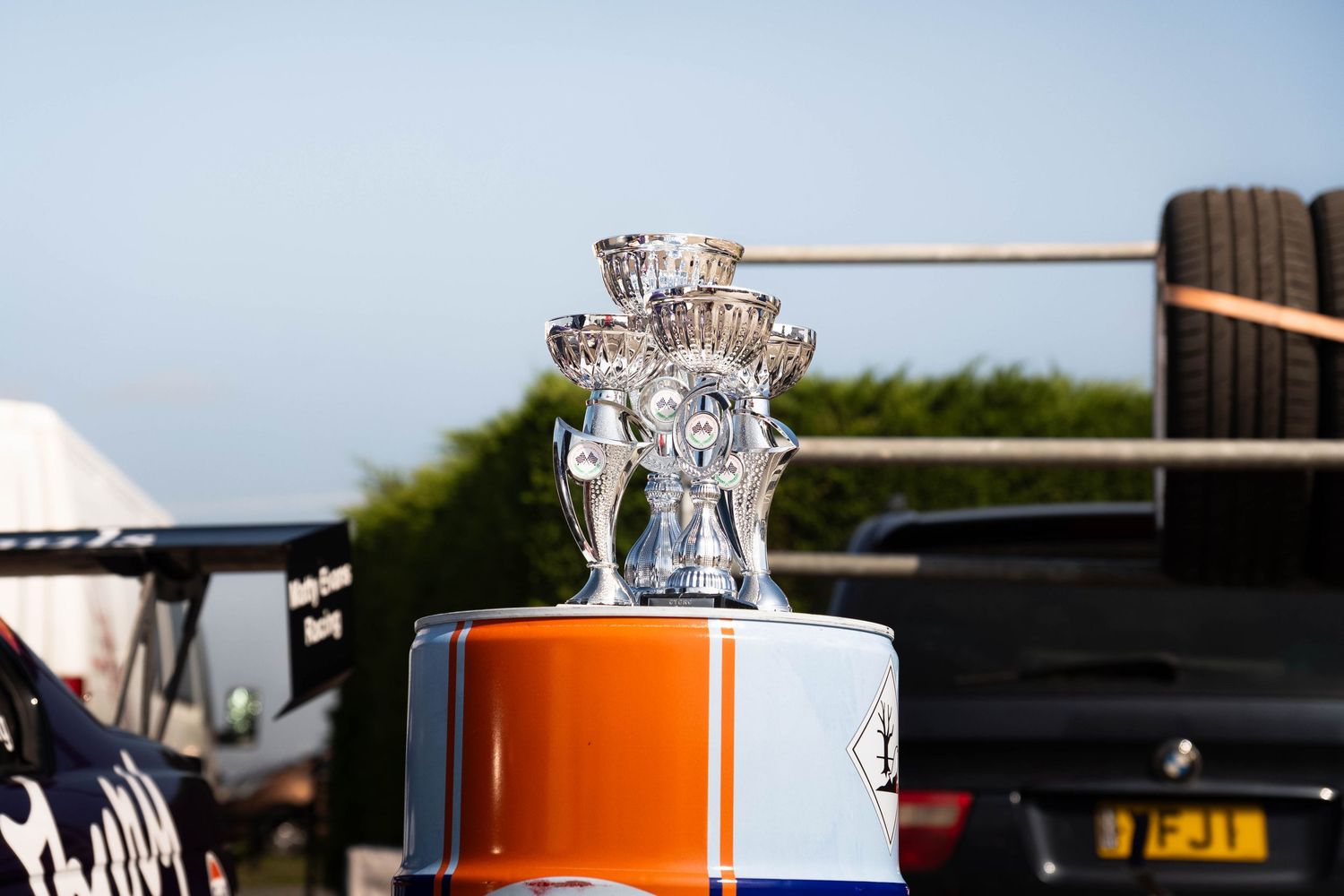 Ornate silver trophy cup displayed on orange and blue Gulf Oil liveried surface outdoors.
