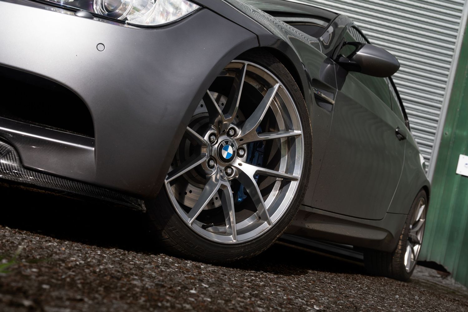Close-up of a BMW M3 alloy wheel with blue roundel badge and grey bodywork.