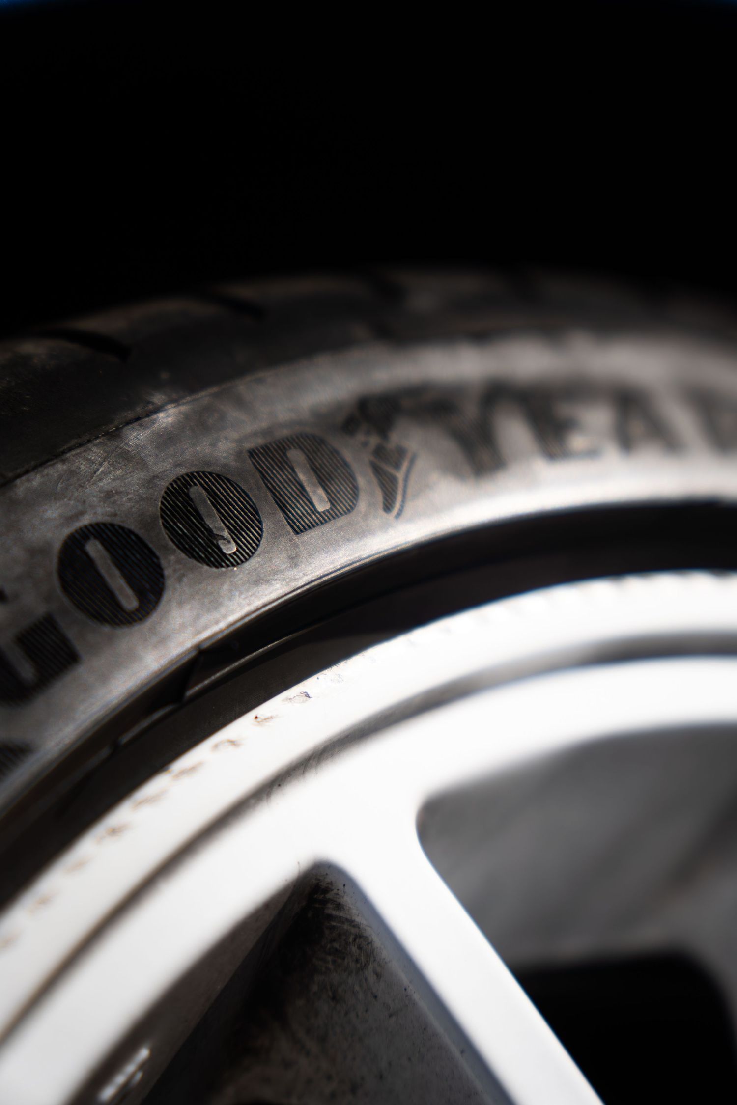 Close-up macro shot of a Goodyear tyre on a silver alloy wheel rim in low light.
