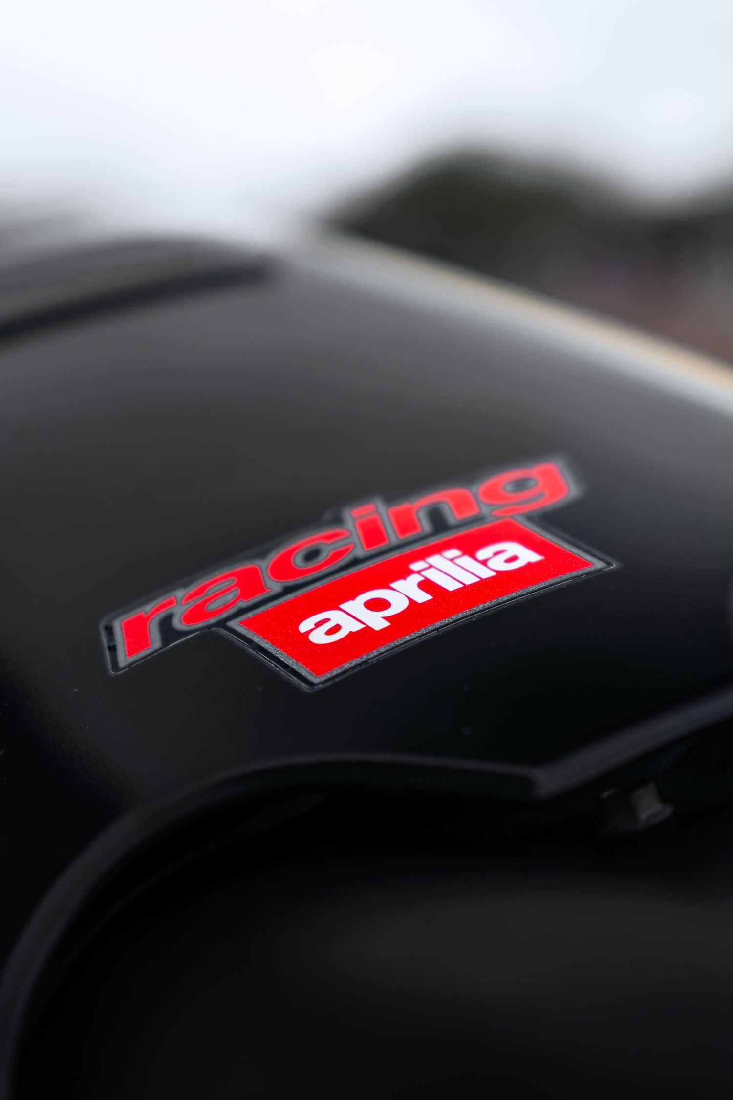 Racing Aprilia logo decal on a black motorcycle fairing with red and white branding.