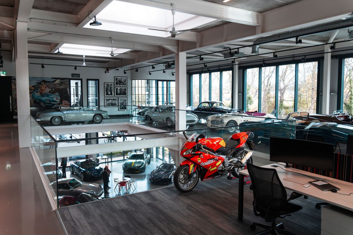 Aerial view of a multi-level luxury car and motorcycle showroom with classic vehicles on display.