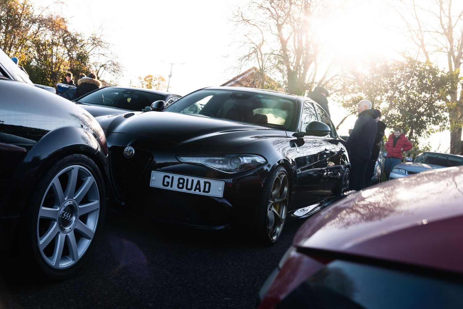 Black Aston Martin with registration G1 BUAD parked at a sunny car meet event.