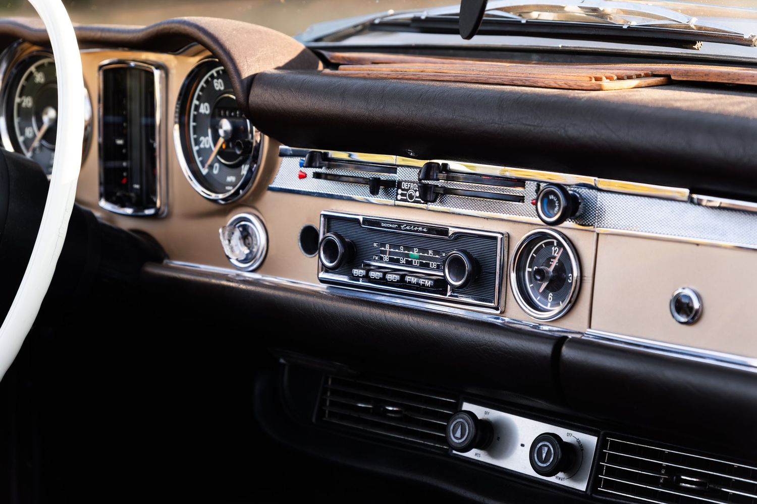 Vintage car dashboard with classic radio, chrome gauges, and retro tan interior detailing on a restored classic automobile.
