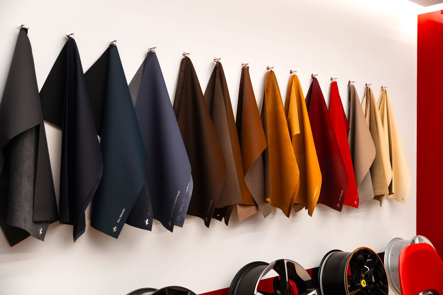 Colorful leather fabric swatches hanging on a white wall display in a luxury fashion or upholstery showroom.