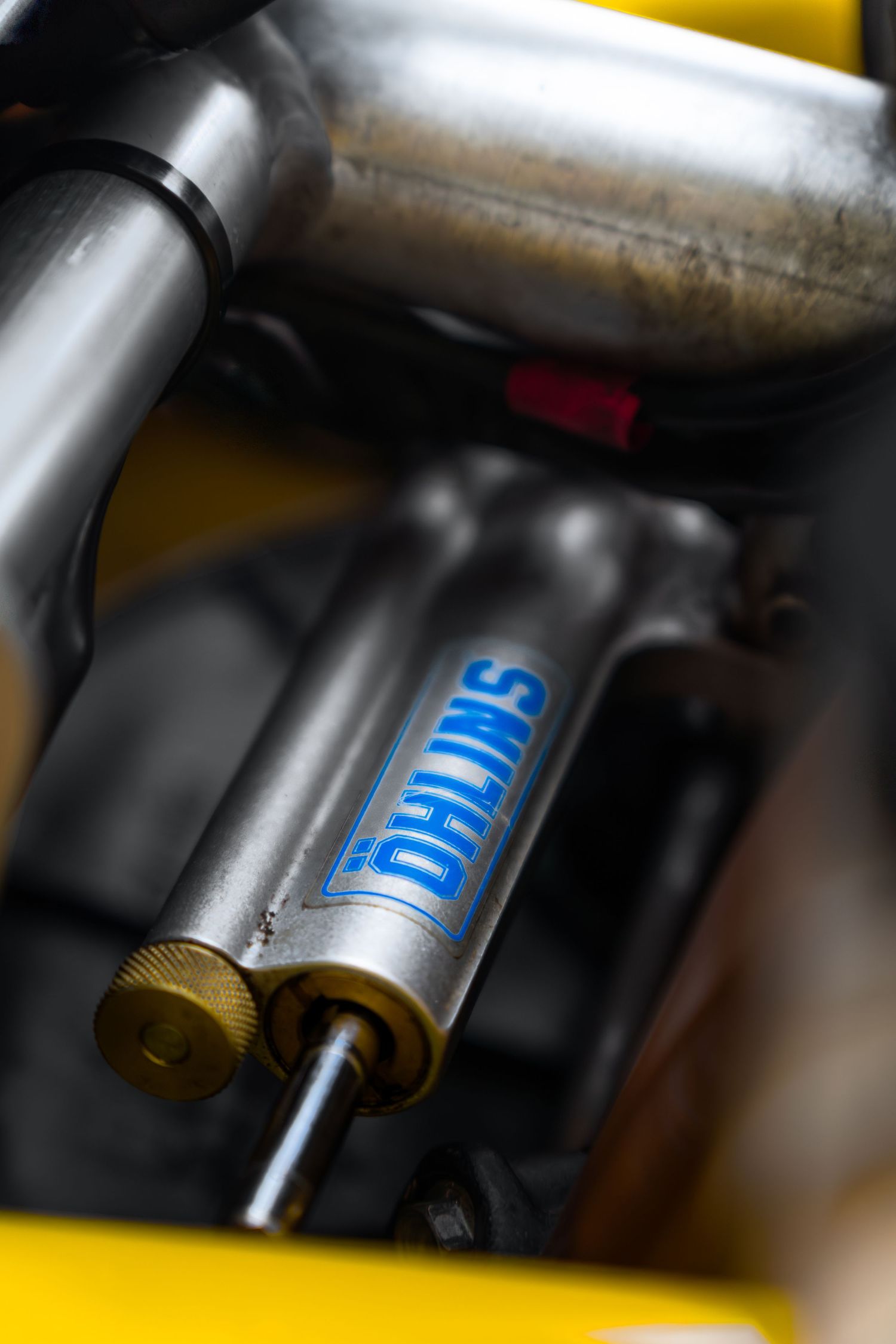 Ohlins branded front fork suspension component on a yellow sport motorcycle close-up.