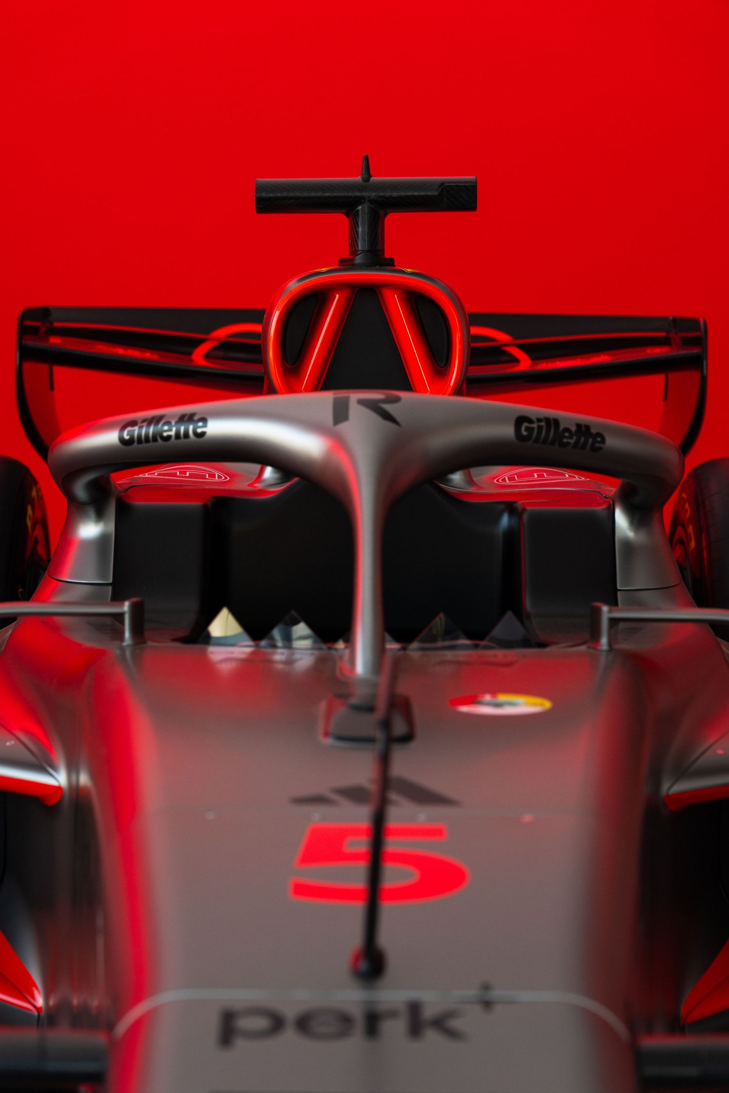 Front view of a Formula 1 race car numbered 5 with Gillette sponsorship against a bold red background.