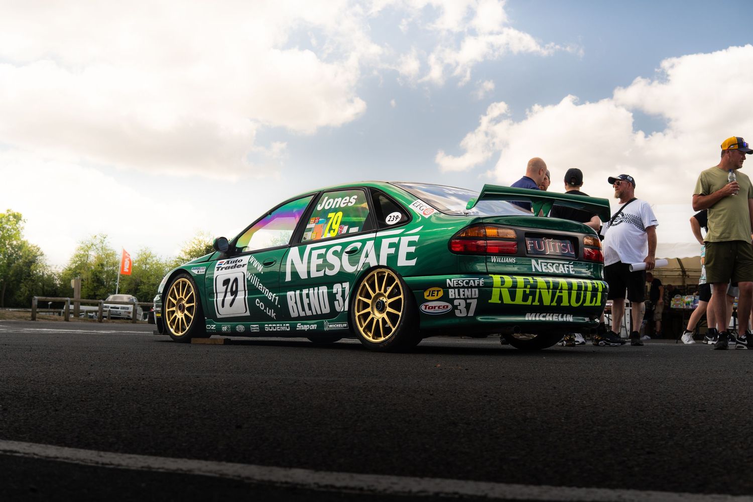 Green Nescafe Renault number 29 touring car at motorsport event with spectators.