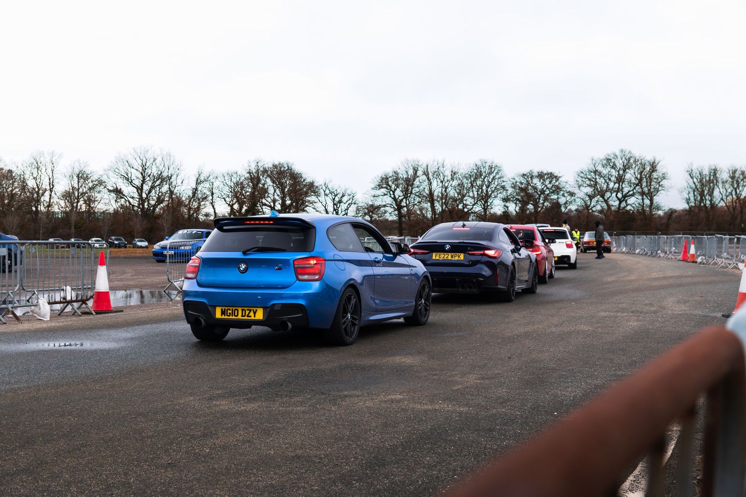 Blue BMW M135i in a queue at a UK car meet event on an overcast day.