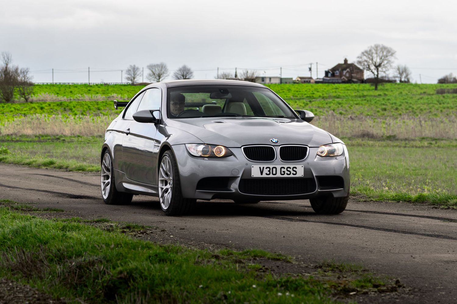 Silver BMW M3 E92 coupe with V30GSS plate parked on a quiet country road.