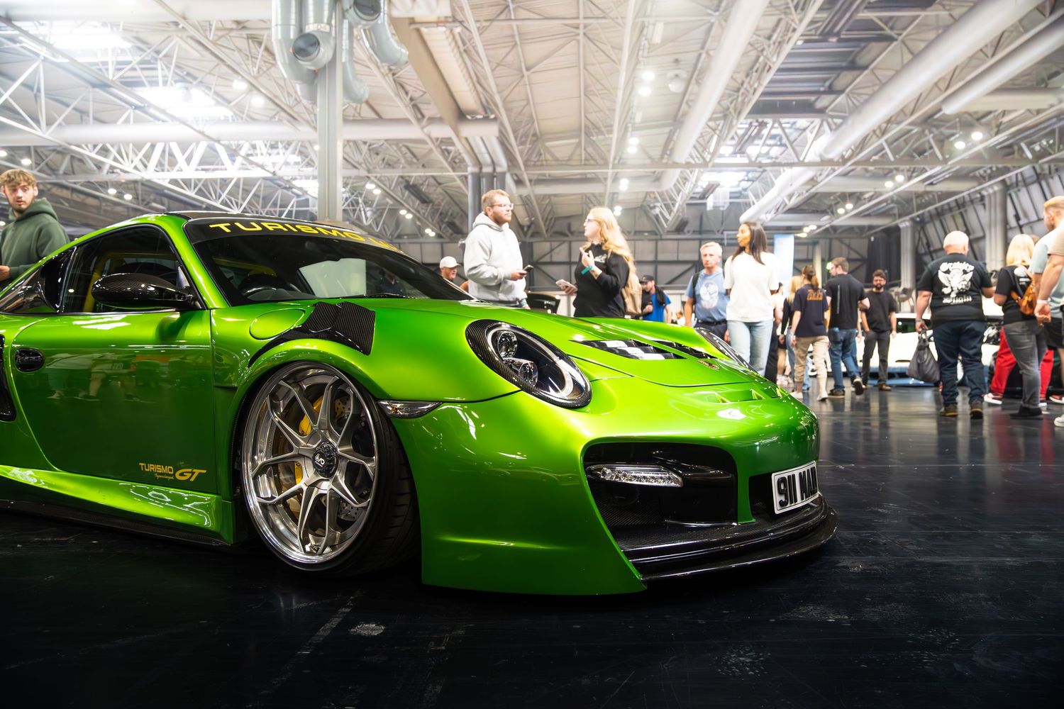 Lime green Liberty Walk Porsche 911 Turbo on display at an indoor car show.