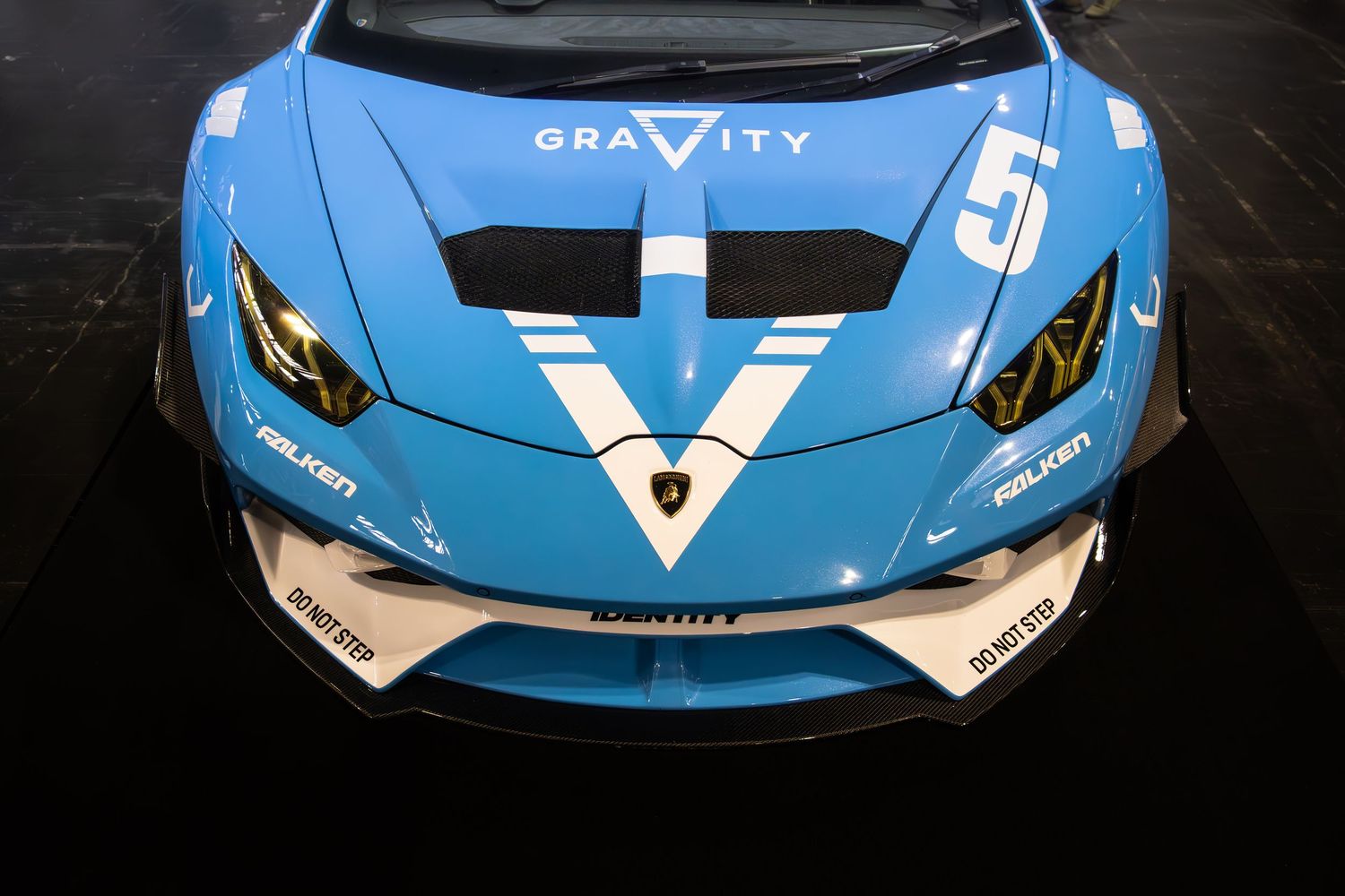 Blue Gravity-branded Lamborghini Huracan race car with white V logo and Falken tire sponsorship on display.