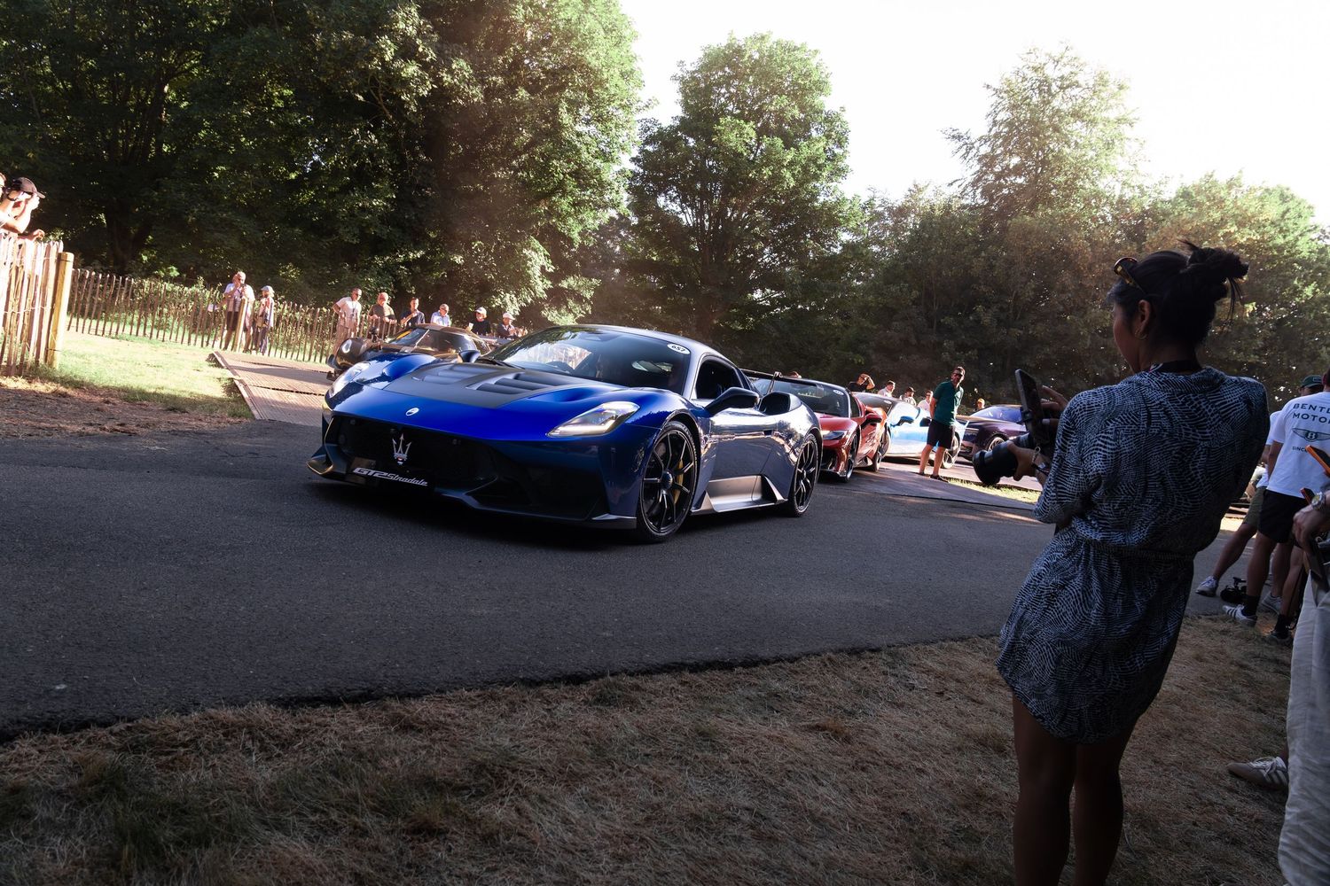 Blue Maserati MC20 supercar on display at Goodwood Festival of Speed surrounded by spectators and trees.