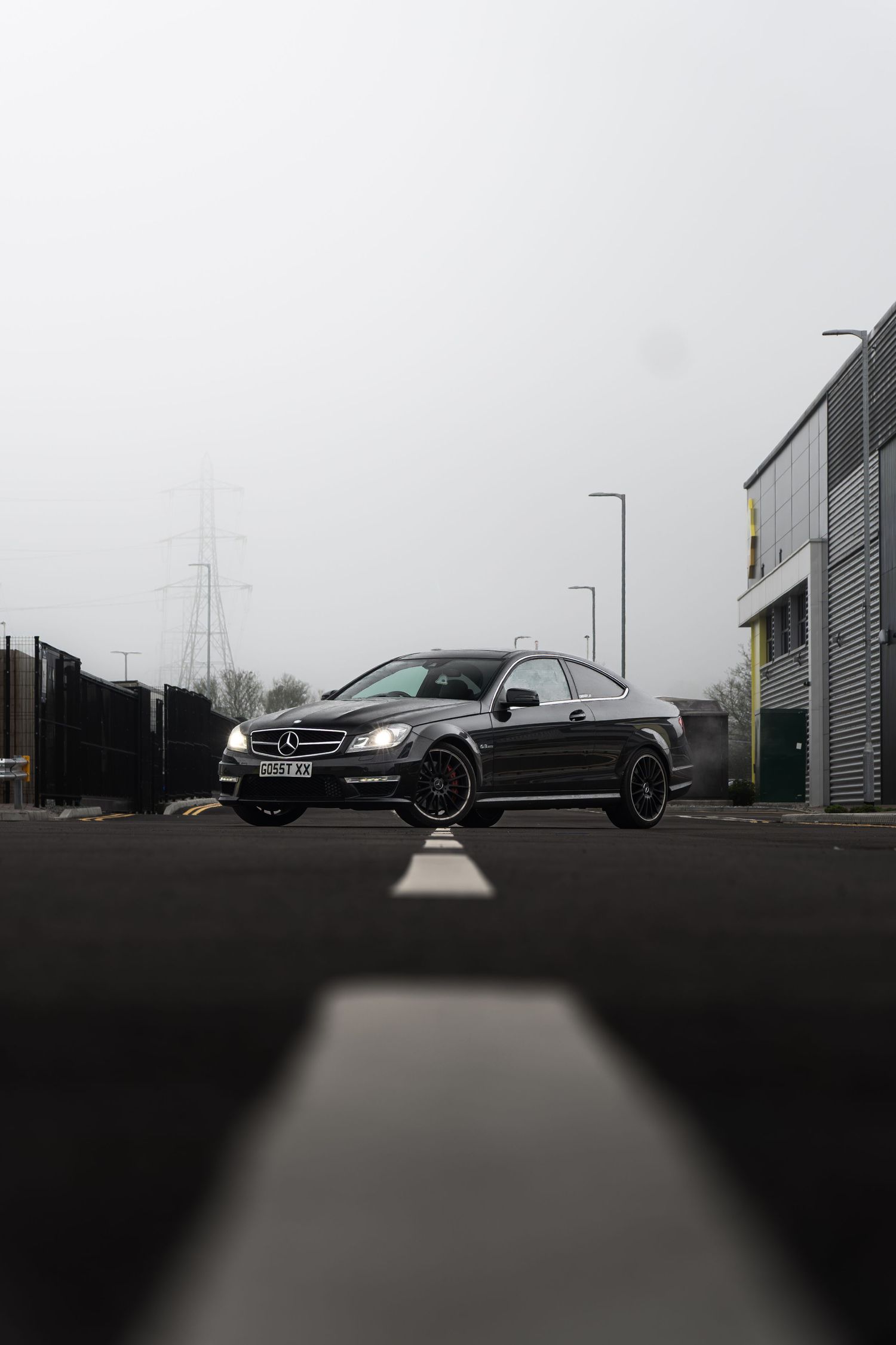 Black Mercedes-Benz C-Class coupe on foggy road with low angle perspective shot.