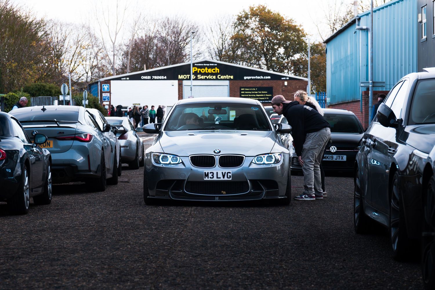 Silver BMW M3 E92 surrounded by cars at a UK car meet near Protech service centre.