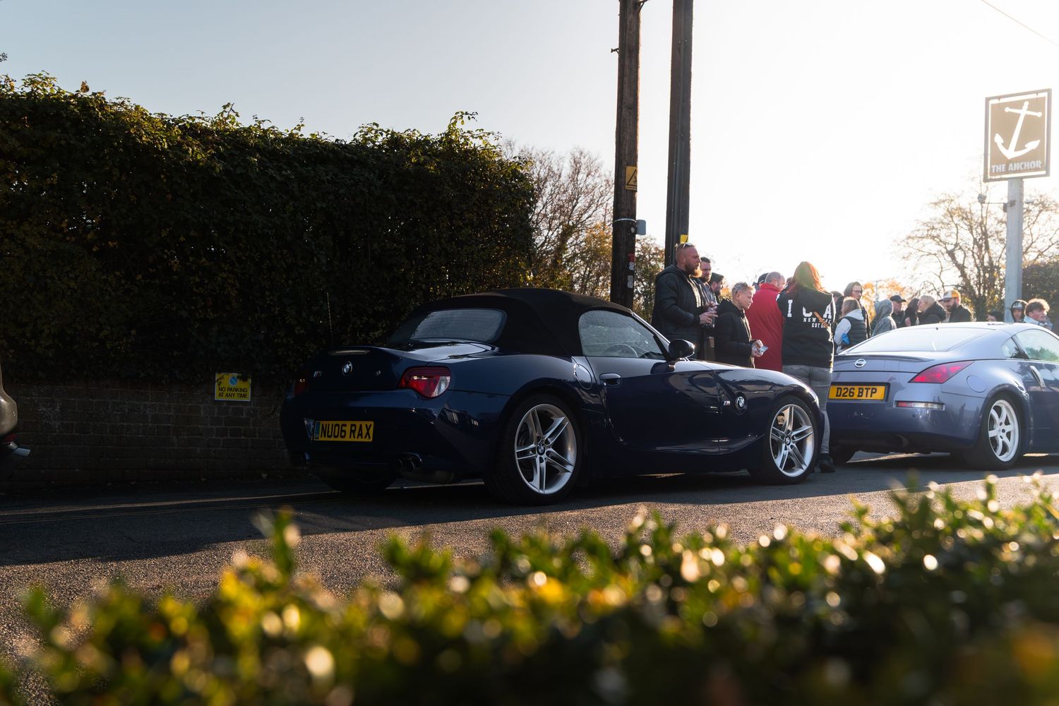 Dark blue BMW Z4 convertible with yellow registration plate at a sunny car meet event.