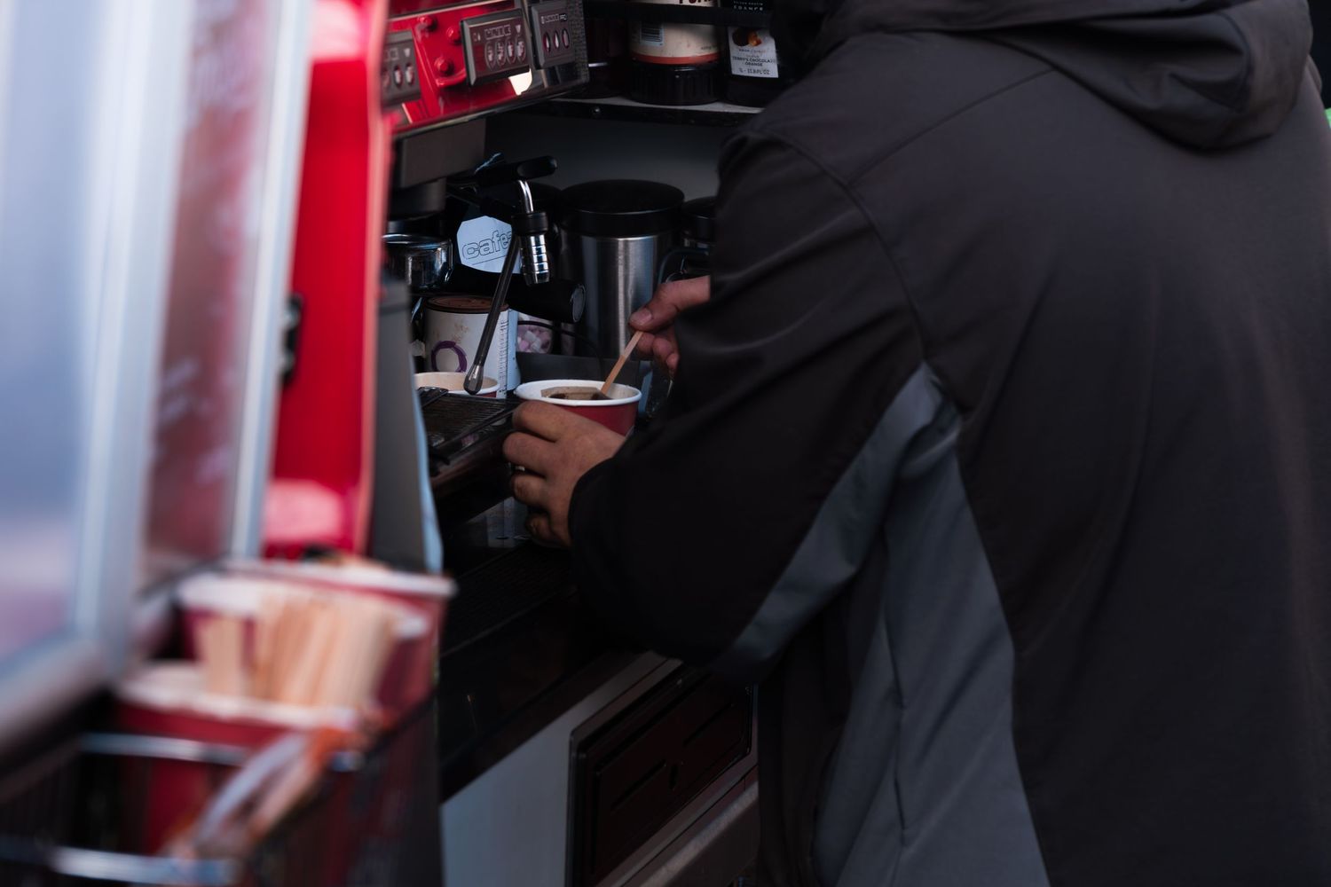 Barista preparing coffee at a professional espresso machine in a cafe setting.