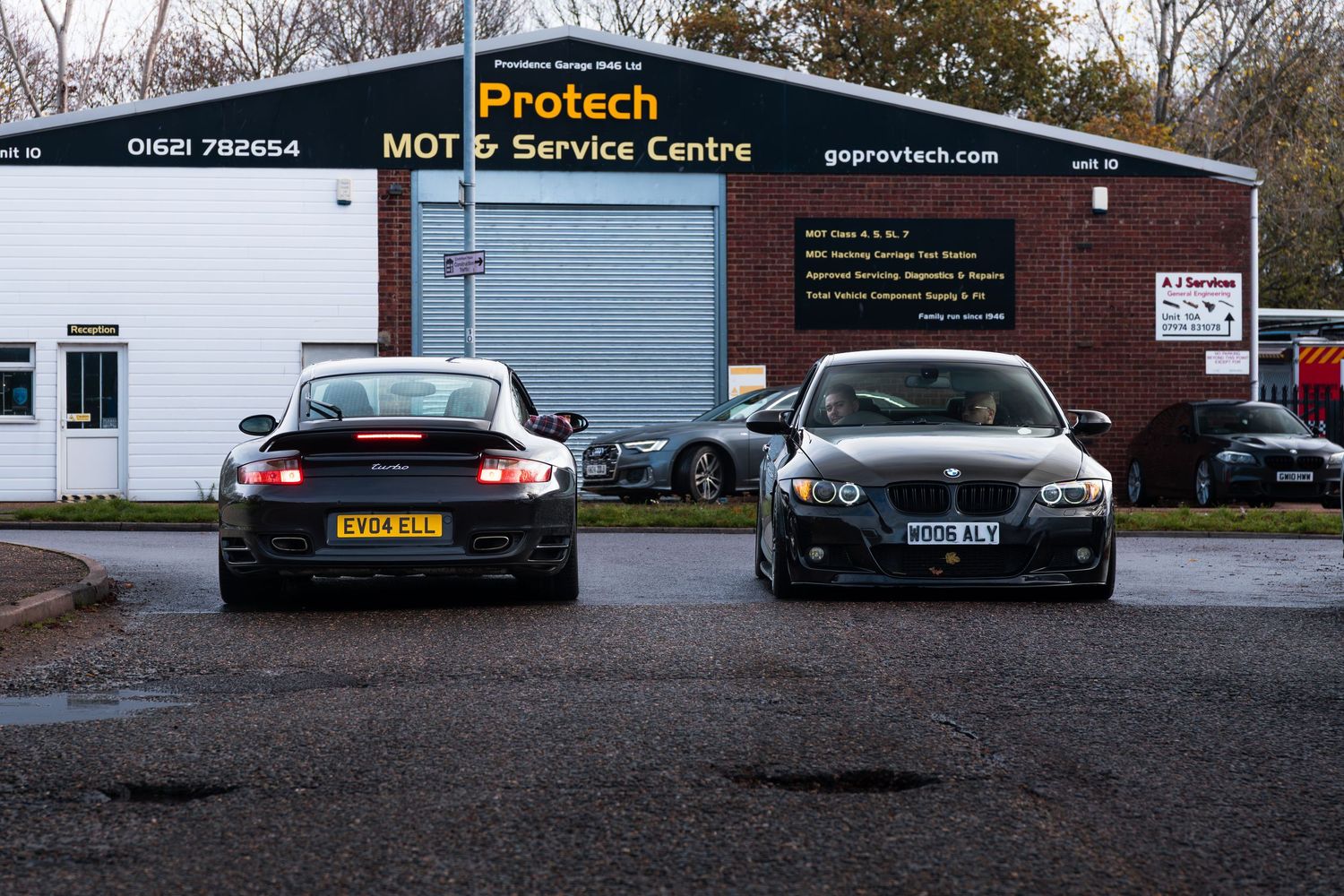 Black Porsche 911 and BMW 3 Series parked outside Protech MOT and Service Centre garage.
