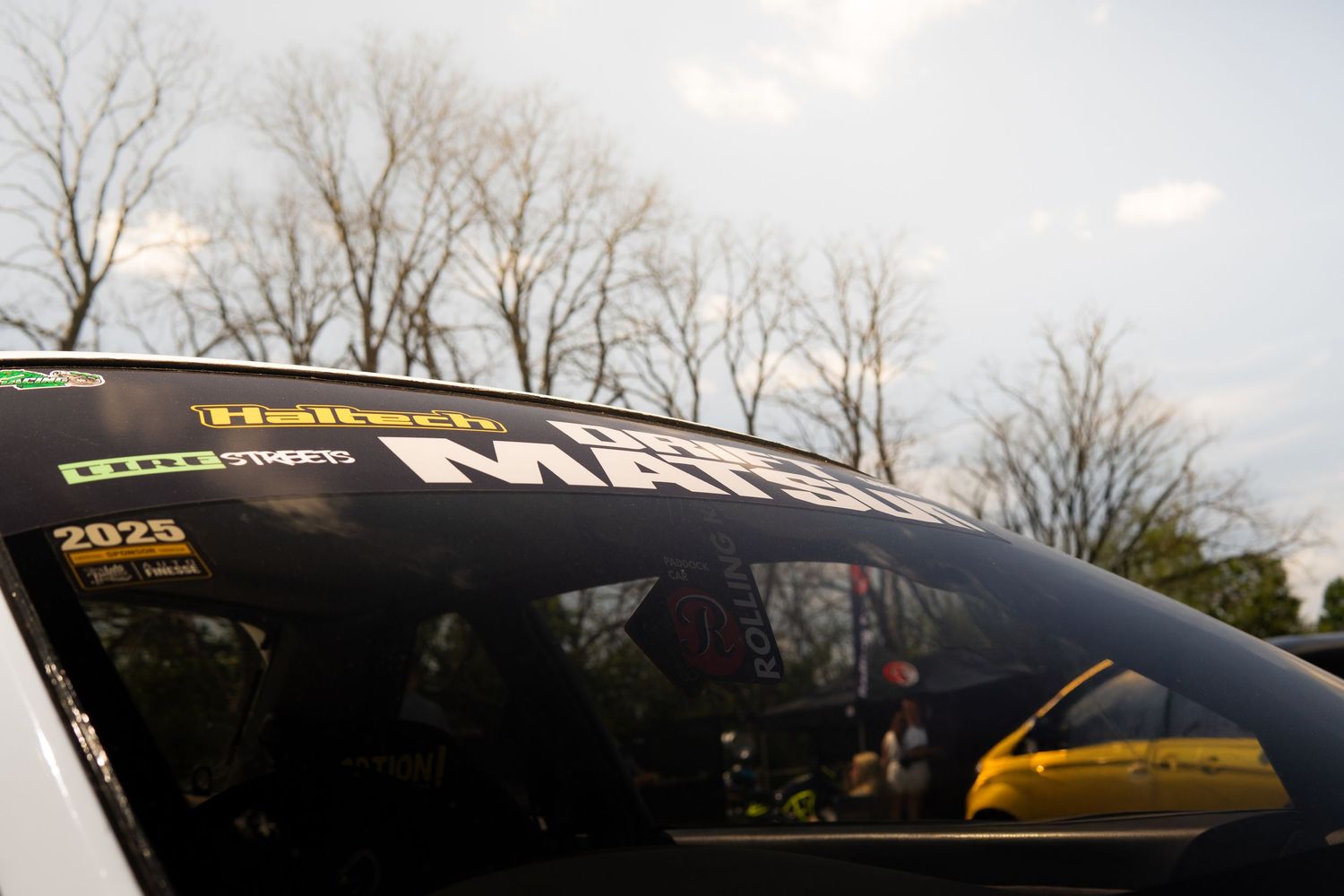 Black rally car windshield with Haltech and MAR sponsor decals at motorsport event.