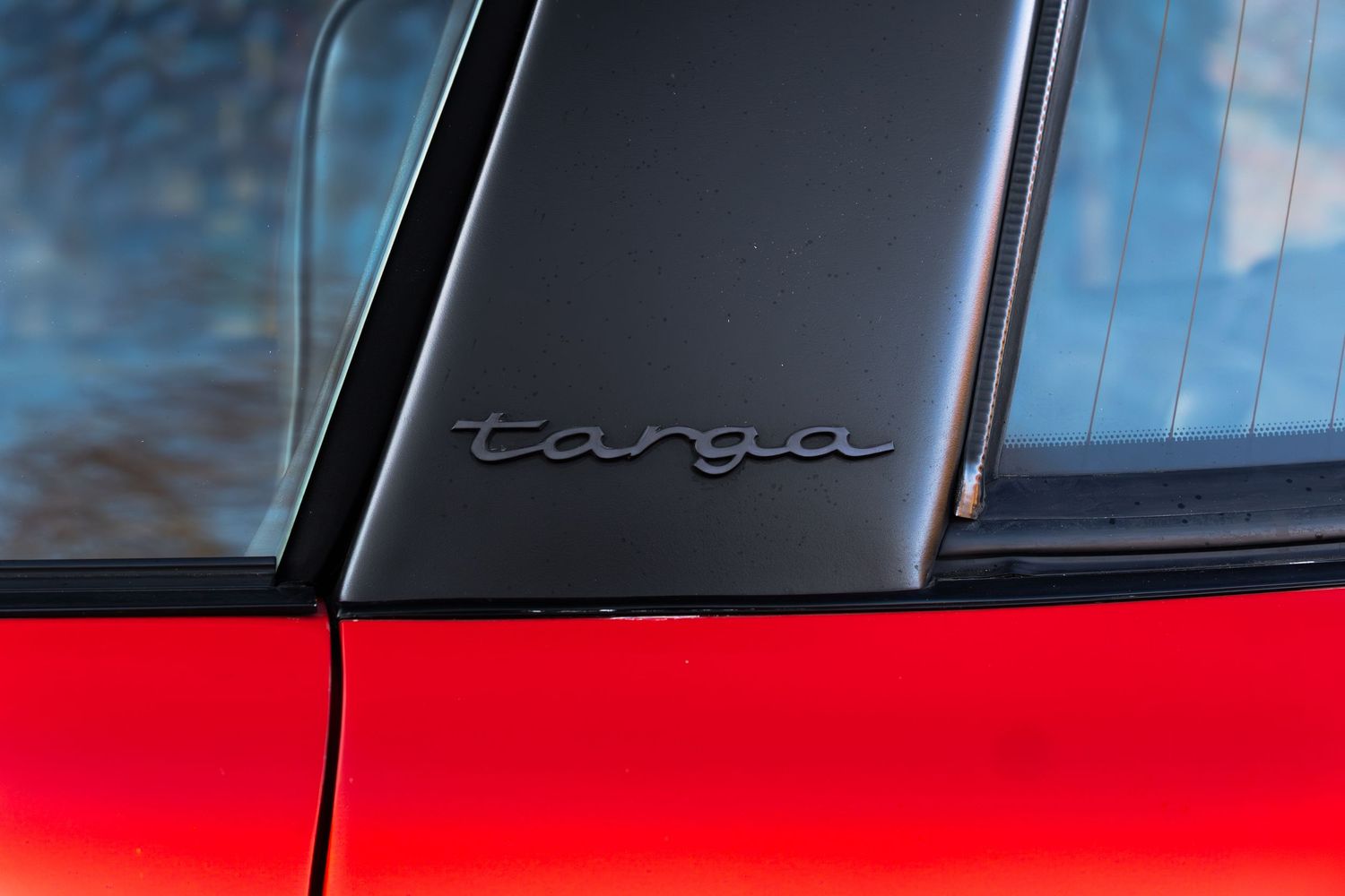 Close-up of the Targa script badge on the B-pillar of a classic red Porsche 911 Targa.