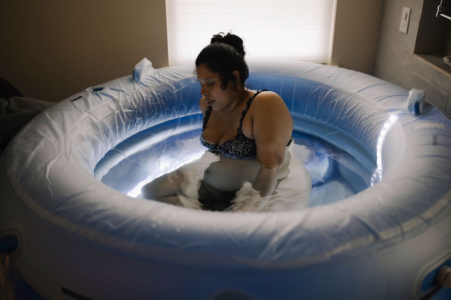 Water birth photo documenting a mother during active labor while seated in a birthing pool.