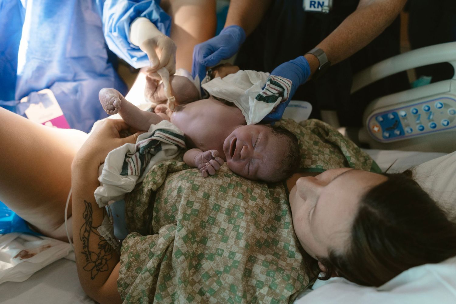 Intimate birth moment capturing a father cutting the cord and welcoming his newborn.