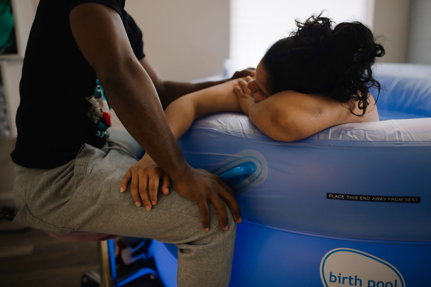 Documentary-style birth image of a mother breathing through contractions in a water birth pool.