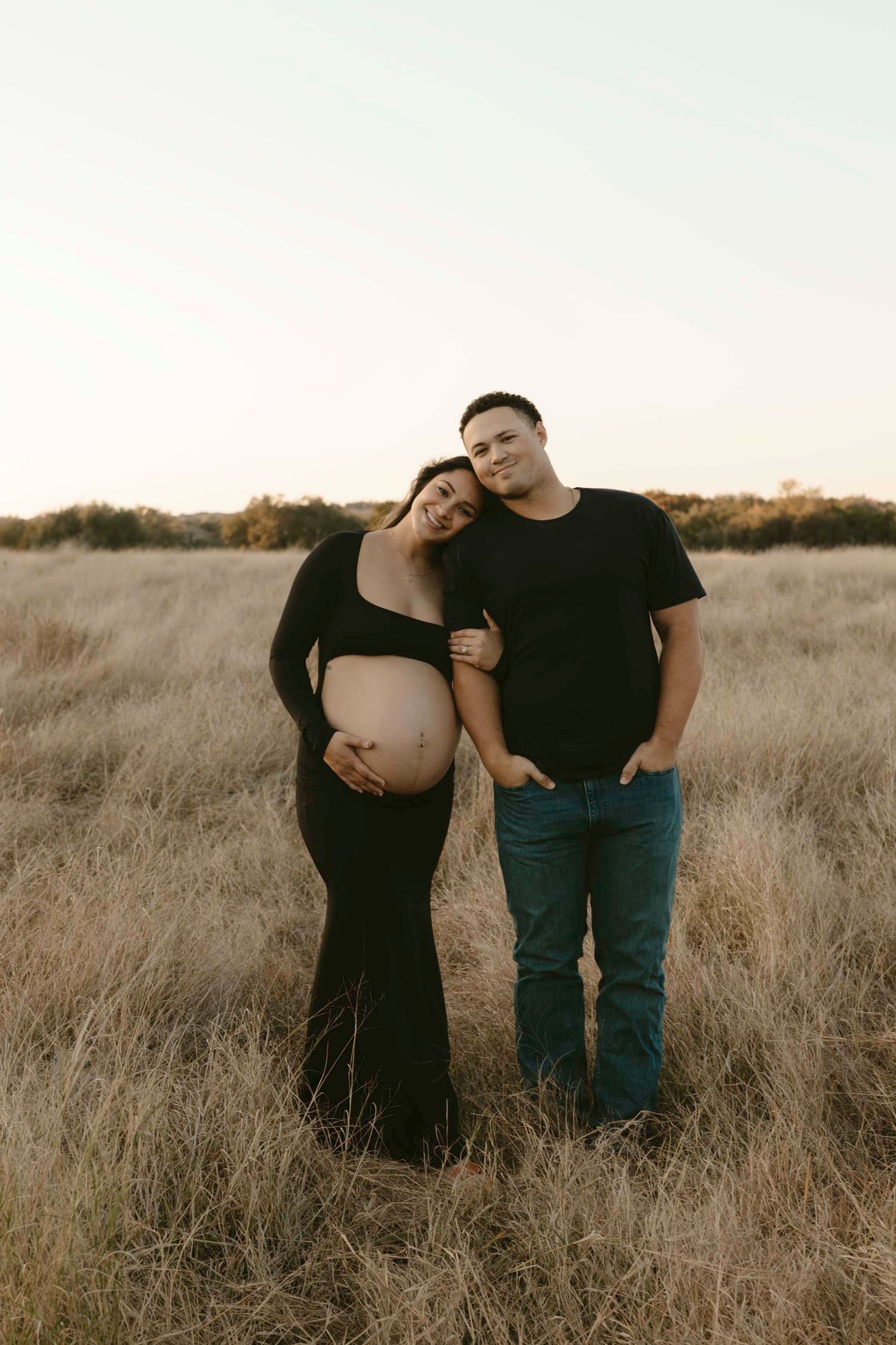 A maternity couple embraces in a golden field of tall grass during sunset, with three similar poses shown side by side.