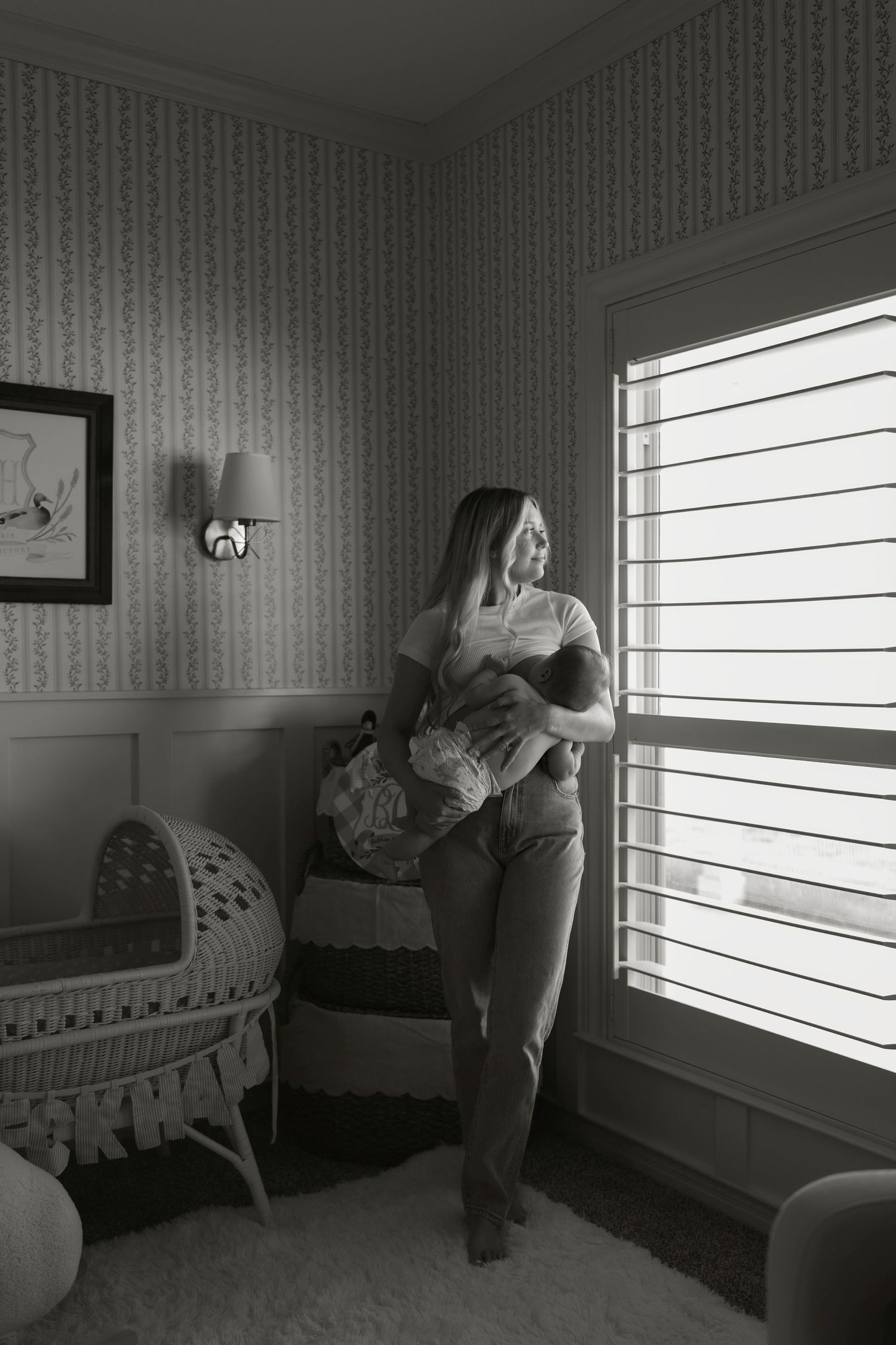 A black and white photo series showing a person looking out a window and breastfeeding her baby.
