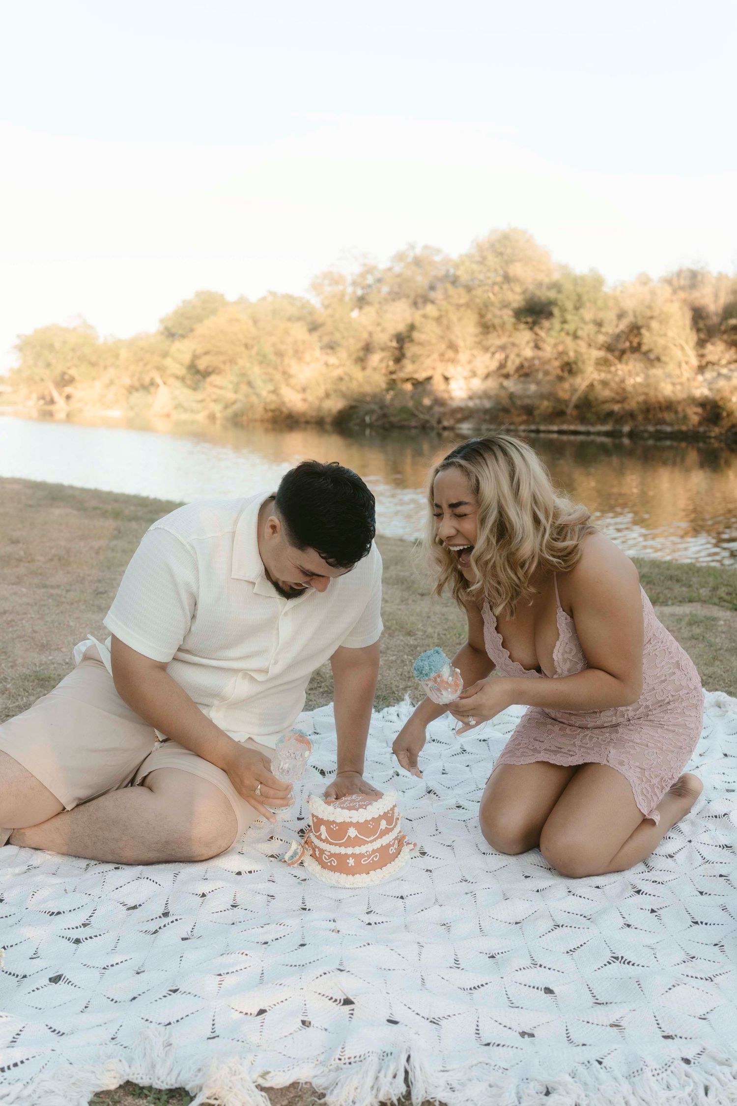 Couple on a crochet blanket playfully smashing cake to find out the gender of their baby.