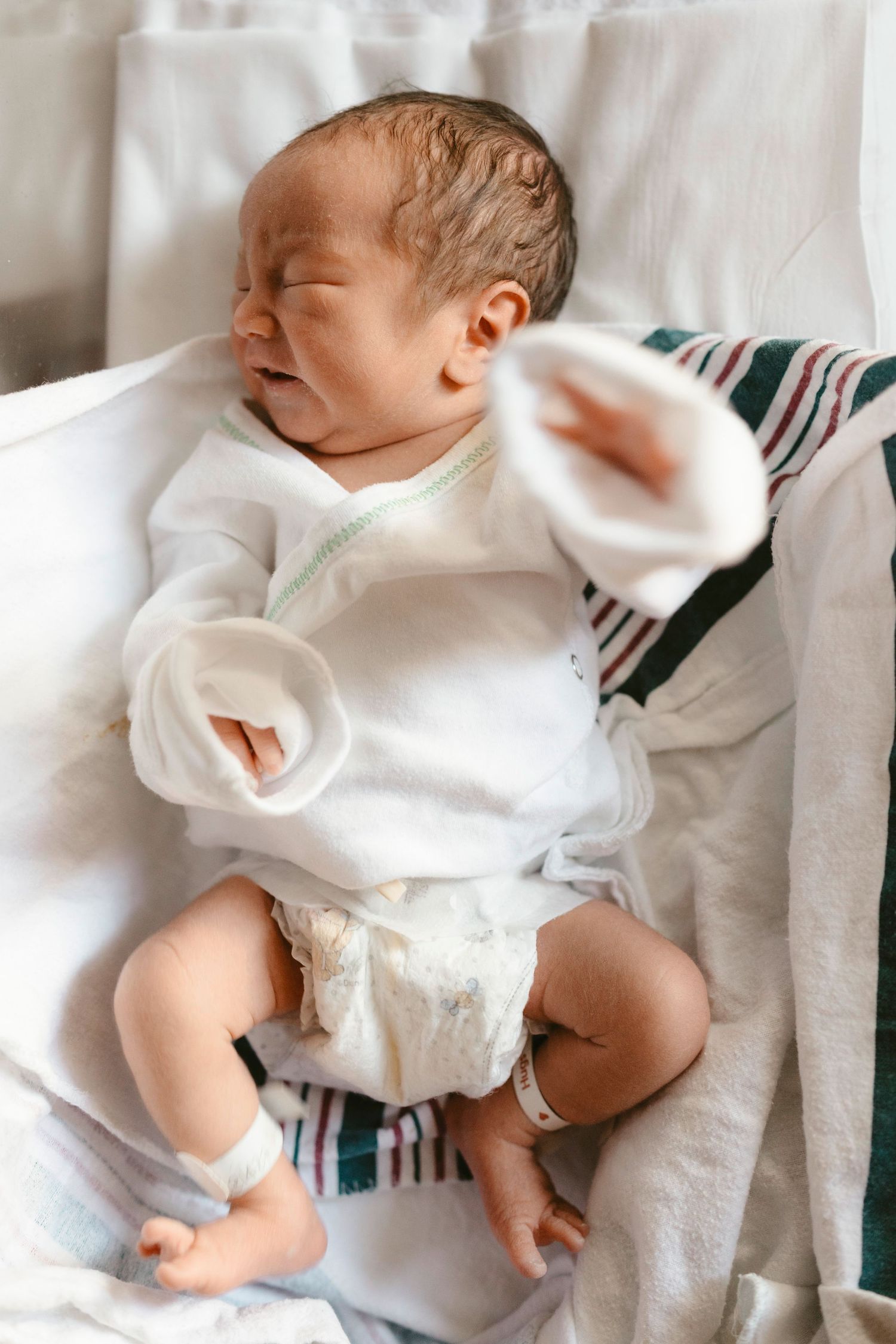 Newborn baby wearing white onesie lies on soft blanket in four similar poses showing peaceful sleeping position.